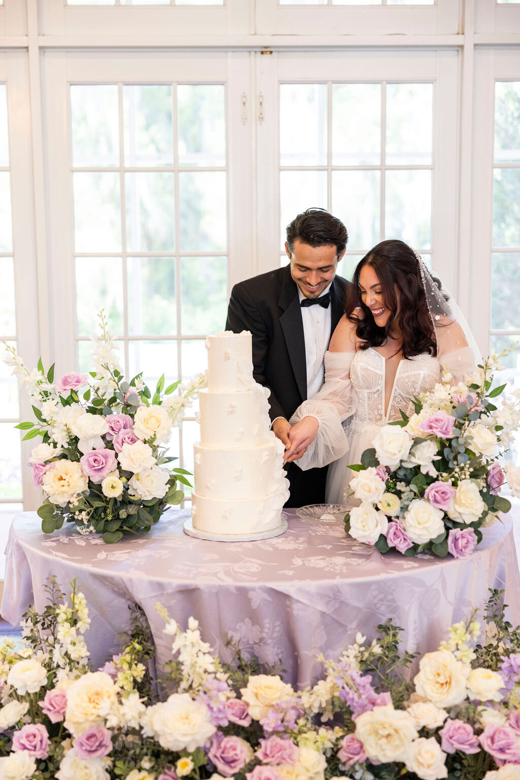 Celebrate your love with a picture perfect cake cutting at the indoor Luxmore Grande Estate in Central Florida. Surrounded by elegant floral decor, this moment highlights the beauty and intimacy of the occasion.