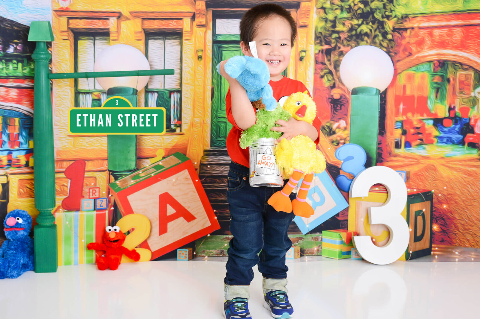 boy holds sesame street characters at his 3rd birthday shoot