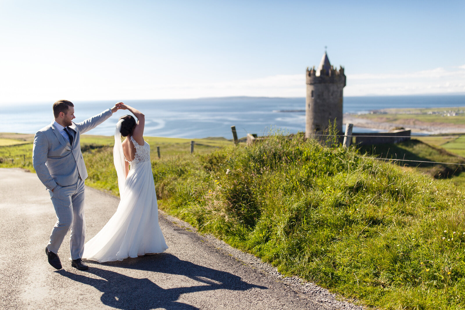 bride and groom dancing in front of a castle in ireland