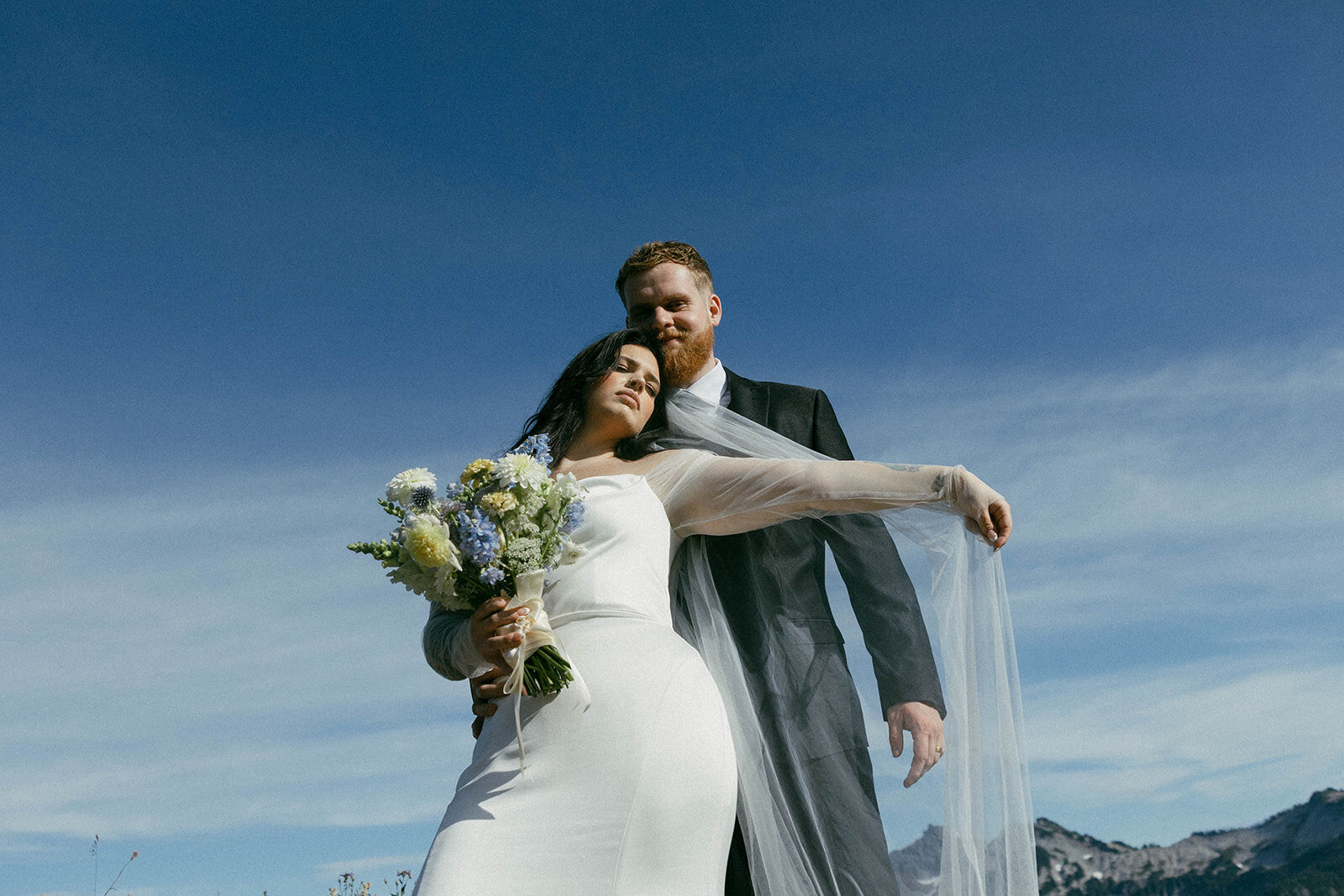 Couple getting married in Glacier National Park Montana, surrounded by yellow summer wildflowers