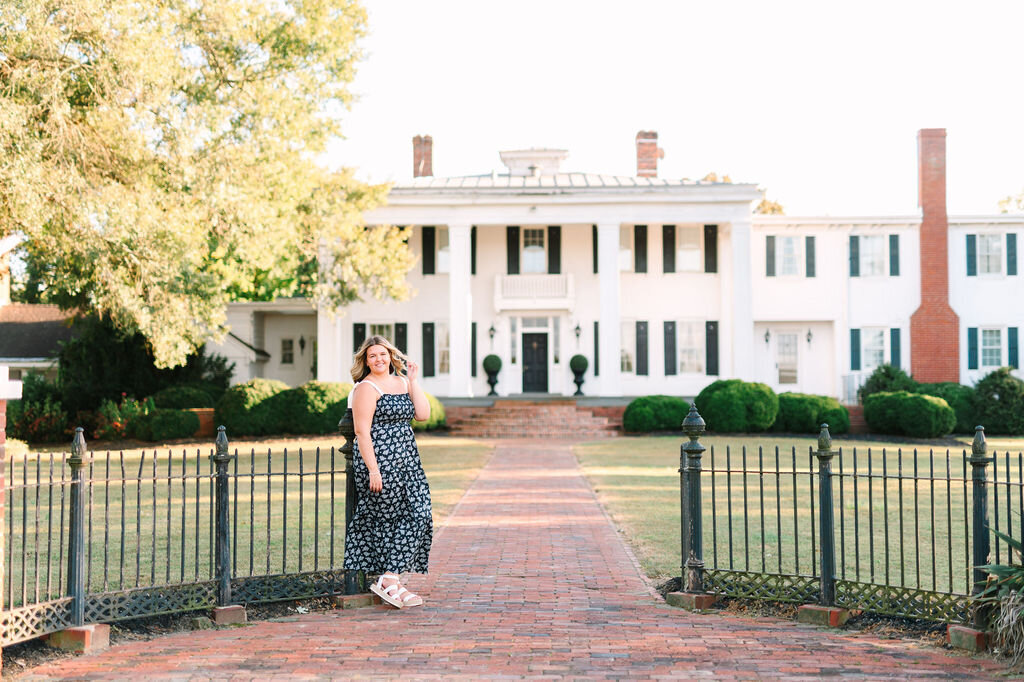 a young woman posing by the entrance to a grand home