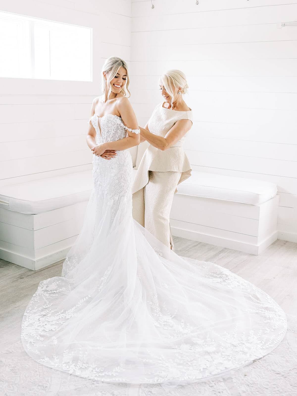 Mother of bride helps her get into her wedding gown on her wedding day