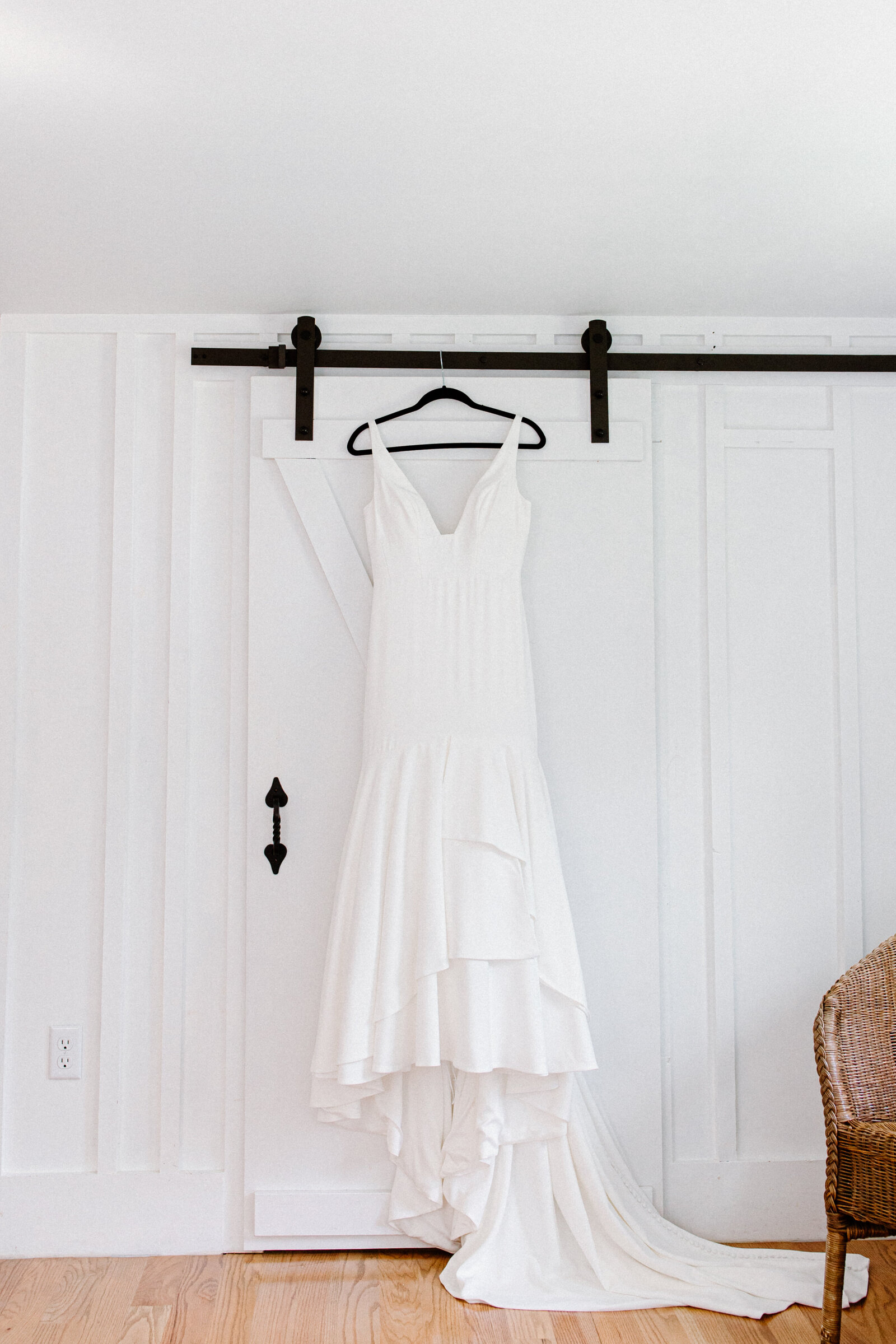 white brides dress hainging from moderm farmhouse sliding door with black iron track and runners