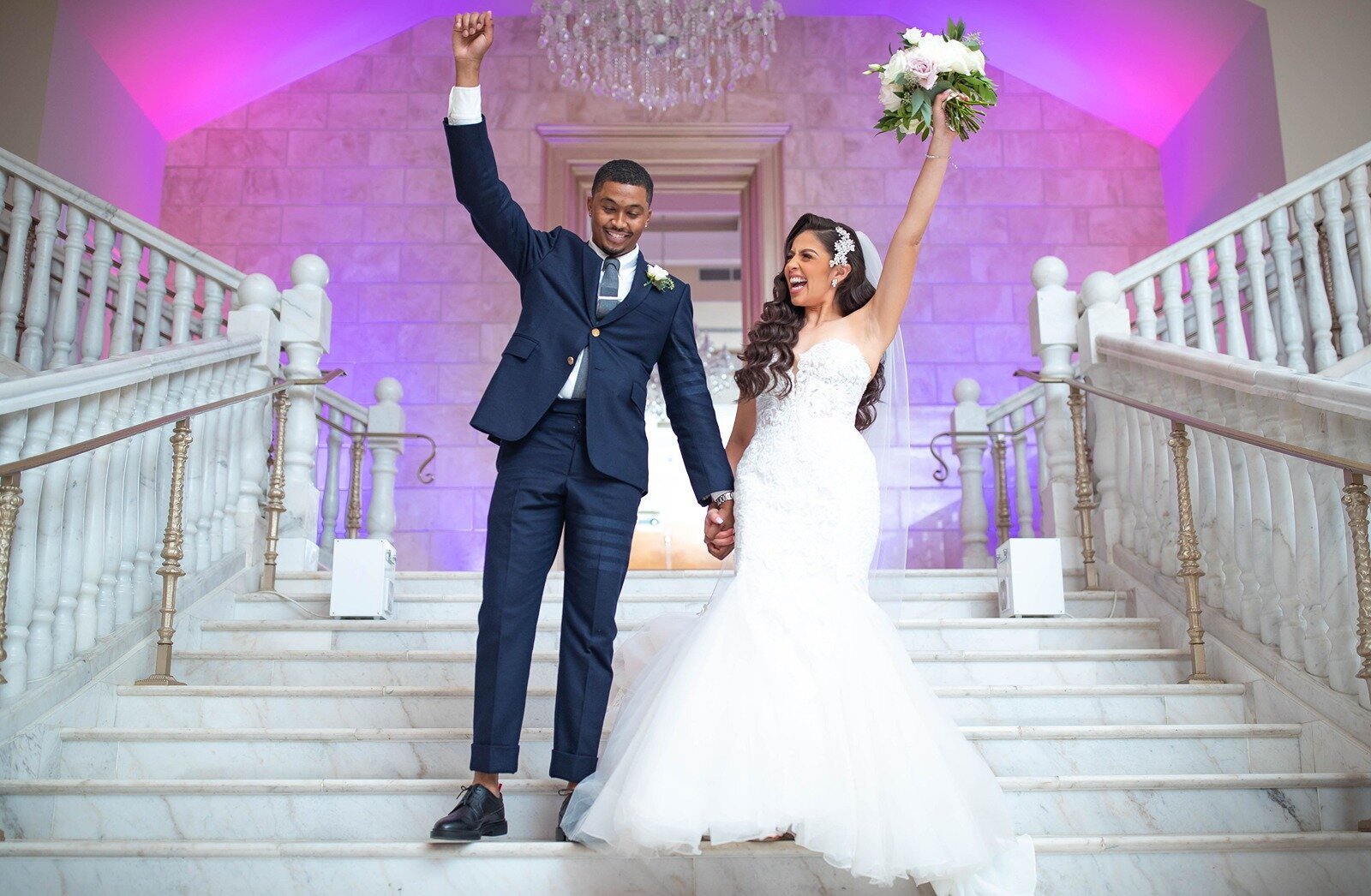 Bride and groom celebrating on grand staircase after wedding ceremony