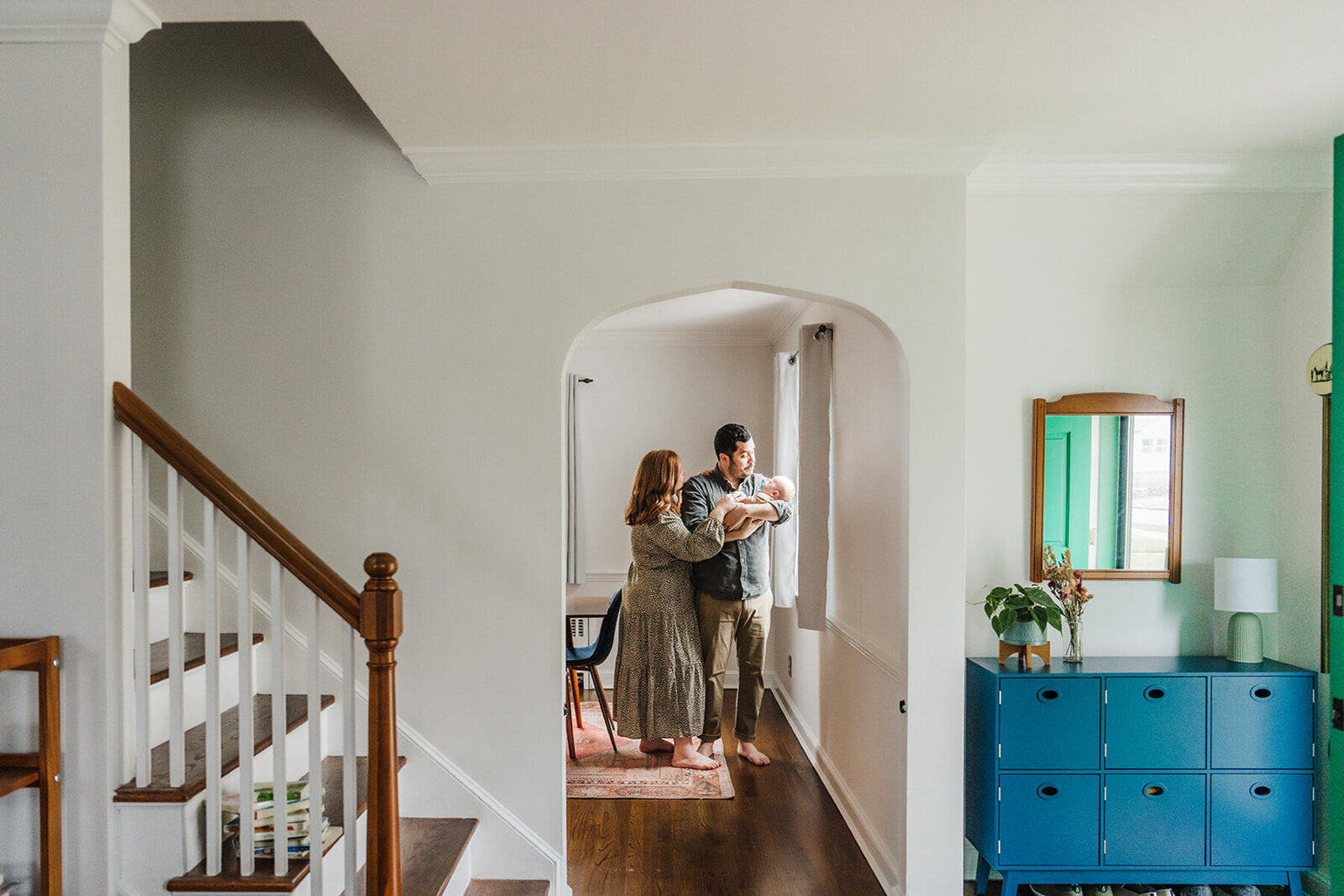 a couple looks at their baby boy underneath an archway in an antique home