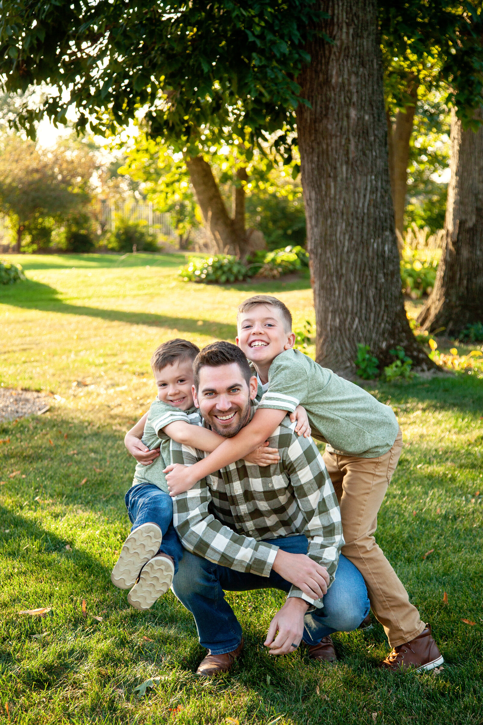 Two sons hanging on dad, all smiling.