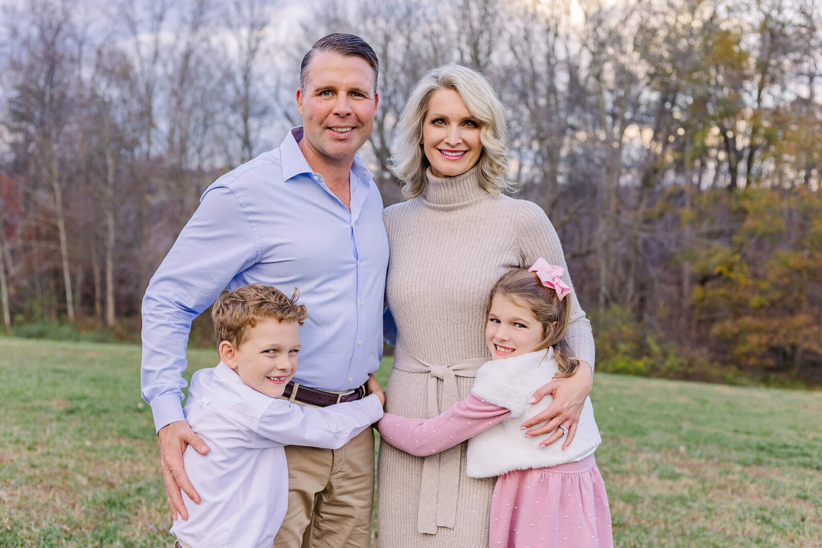 A family of four snuggling in a field during a family photo session in Burke, Virginia.