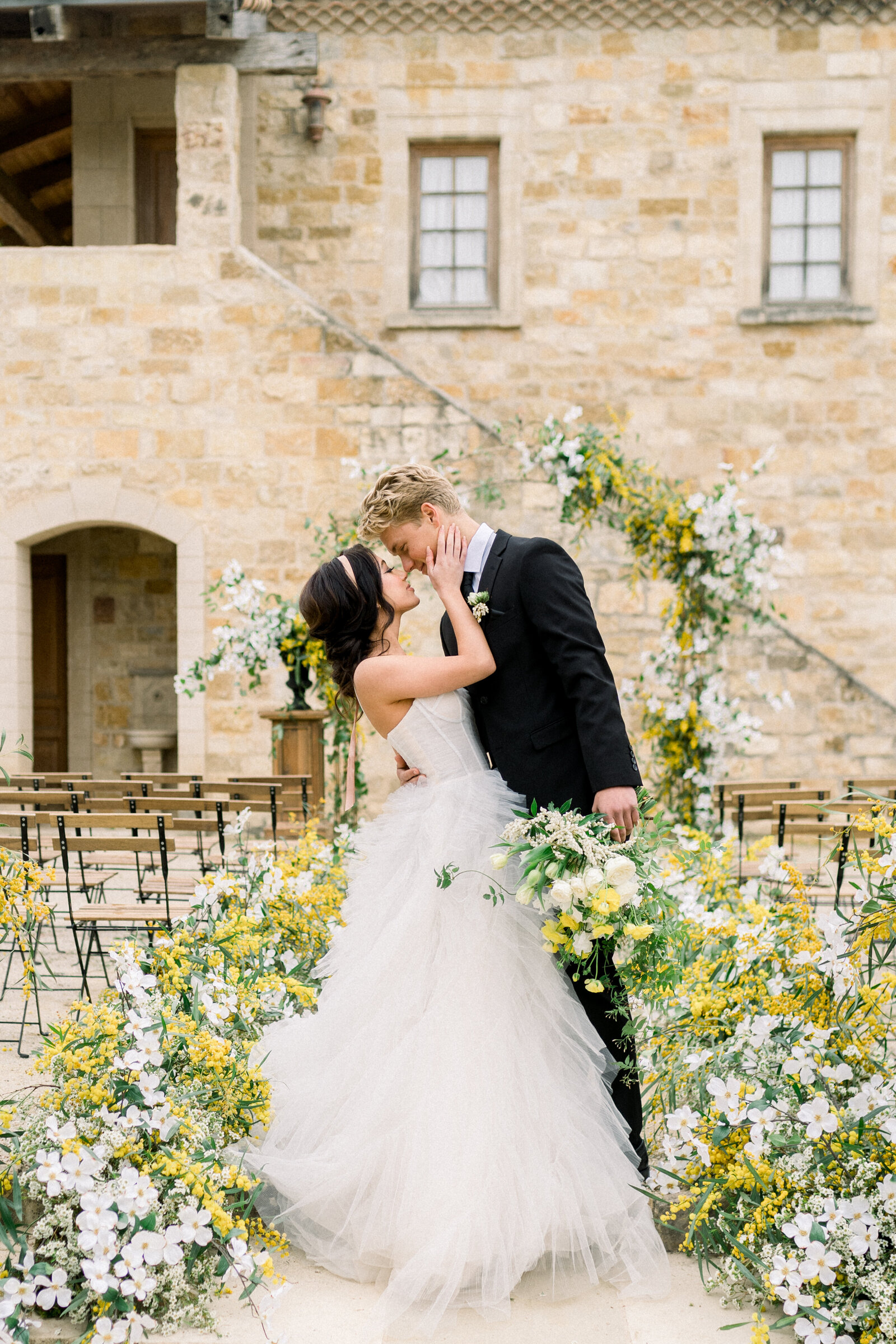 Capturing a magical moment at Sunstone Winery in Santa Ynez, CA, this image by Tiffany Longeway showcases a bride and groom's first kiss, framed by the vineyard's natural beauty.