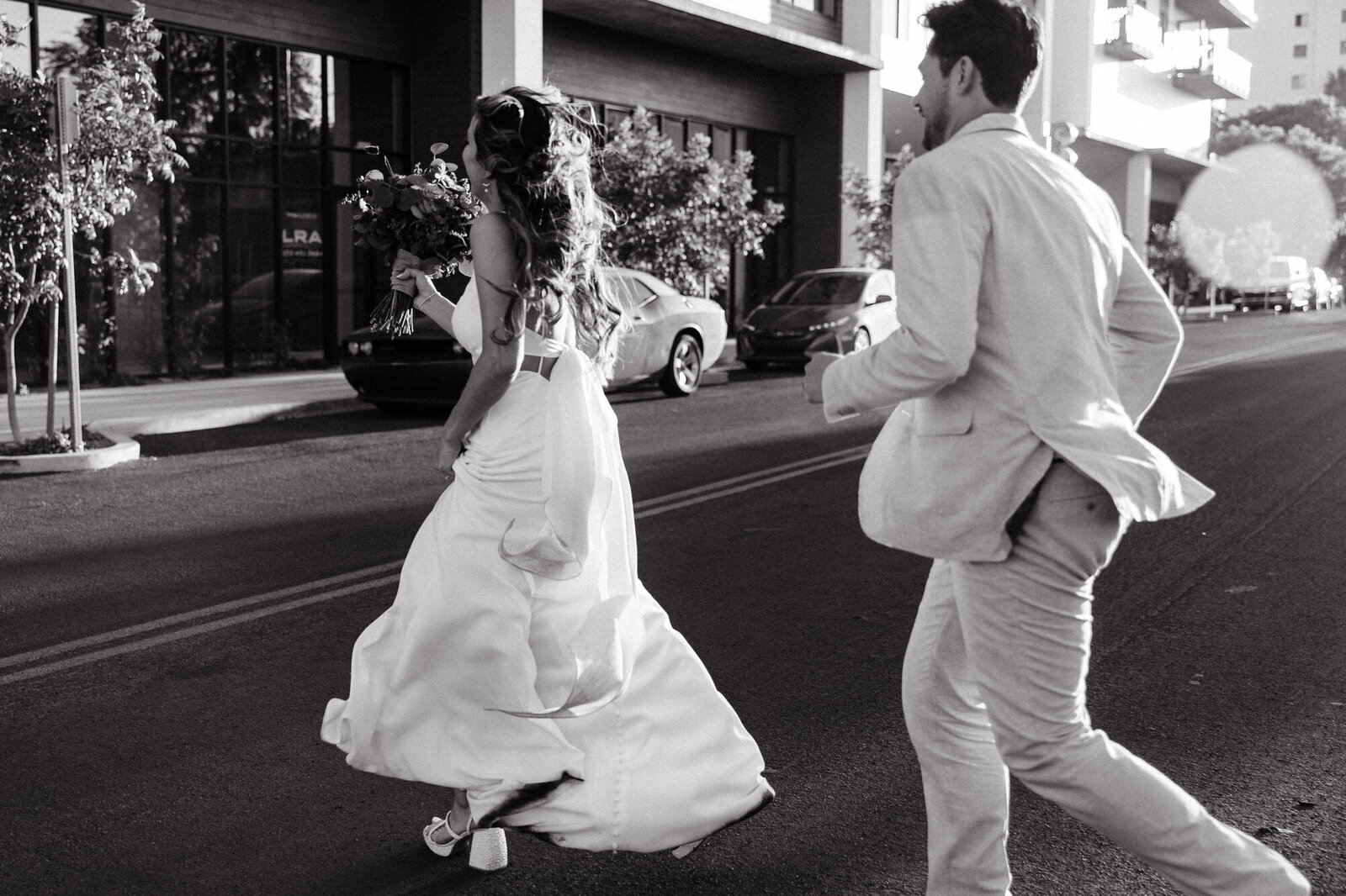 Bride and groom running on street captured by wedding photographer in Arizona
