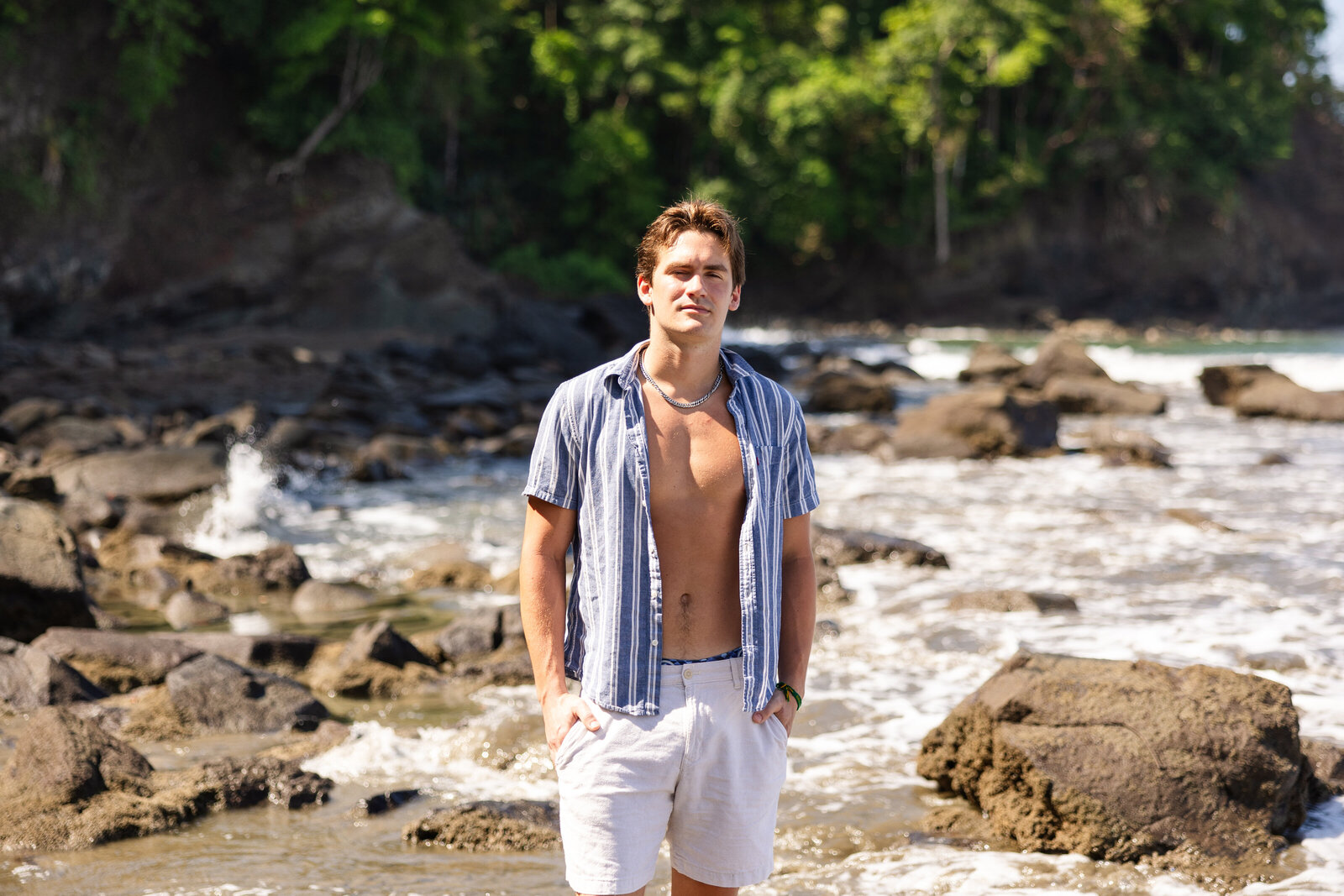 portrait of man with shirt open and ocean waves crashing