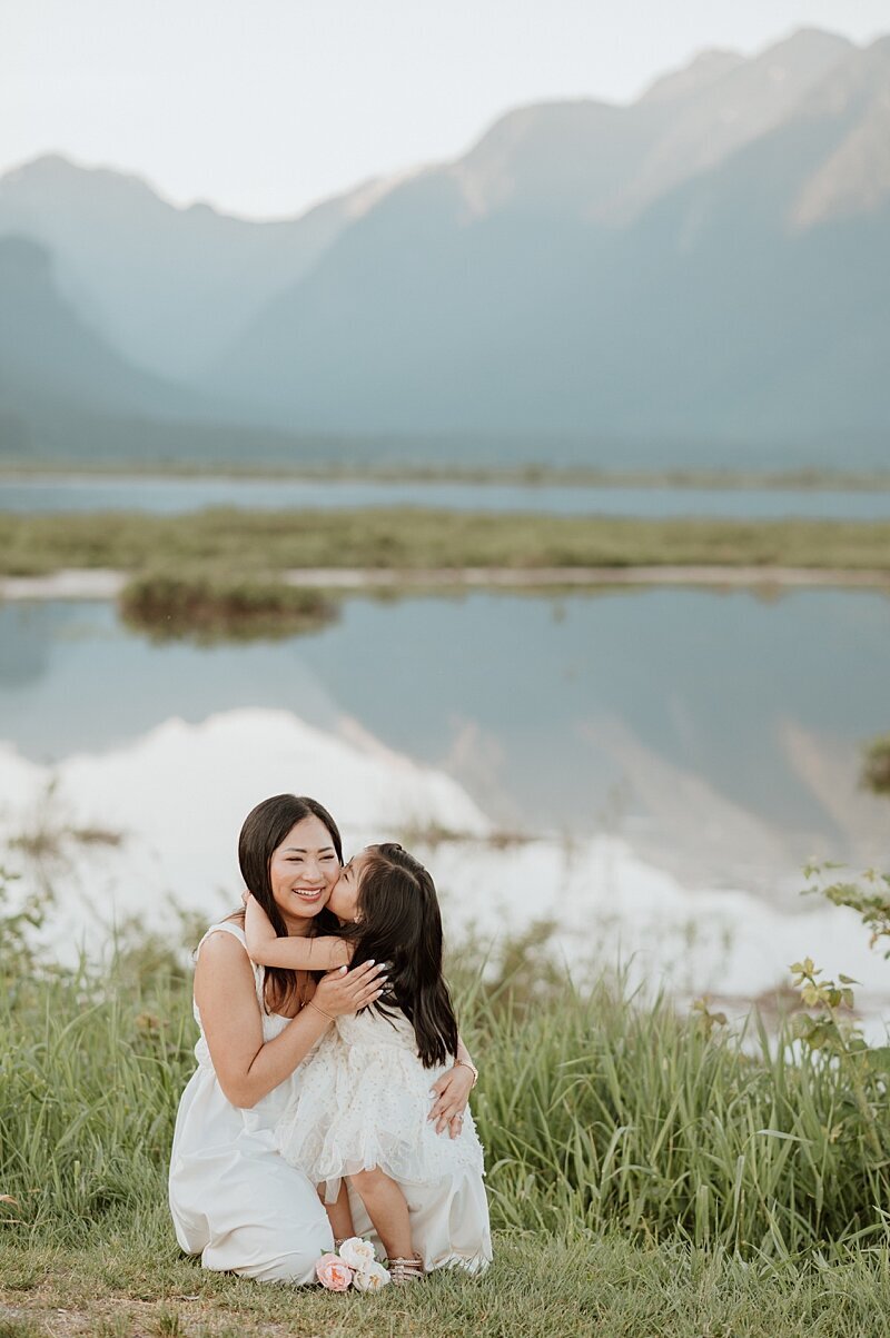 Mom and daughter snuggling on the edge of a lake in Vancouver, BC