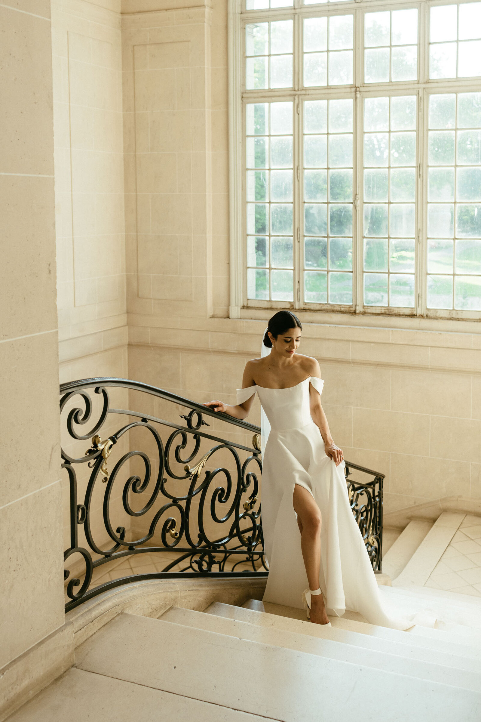 A bride poses in on a chateau staircase at a French destination wedding in Paris.