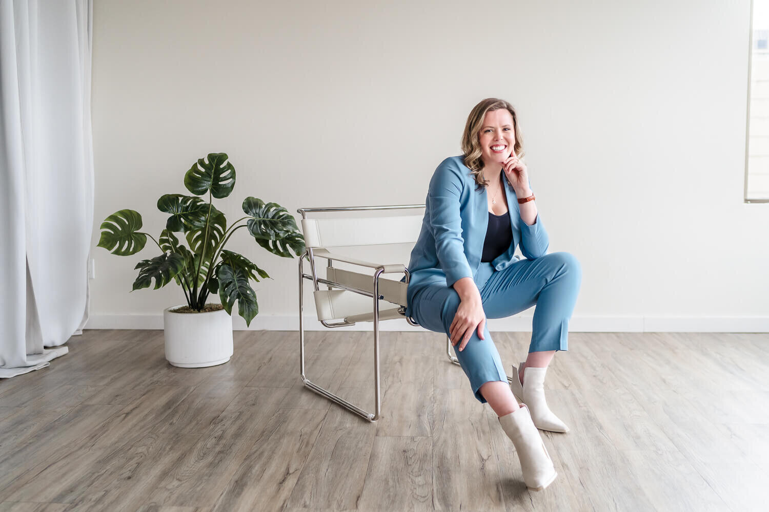 Entrepreneur in blue suit sitting confidently in modern white chair in indoor Kelowna studio