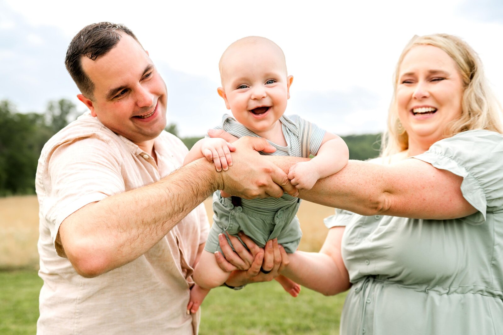 mom and dad looking at smiling 6 month old baby boy