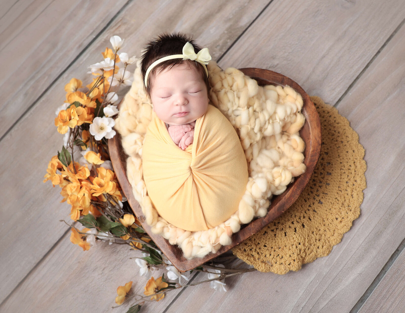 Newborn girl in wooden heart bowl at our studio in Rochester, Ny.