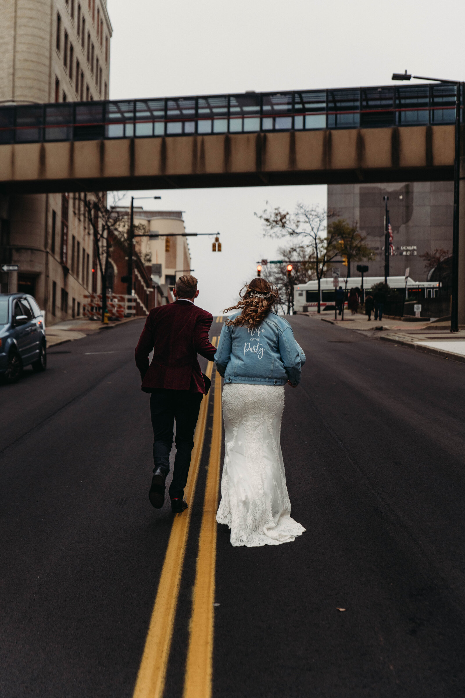 Bride and Groom run up a street in downtown Akron on winter day.