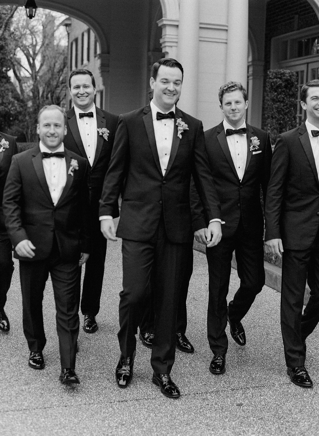 black and White of groom walking with groomsmen