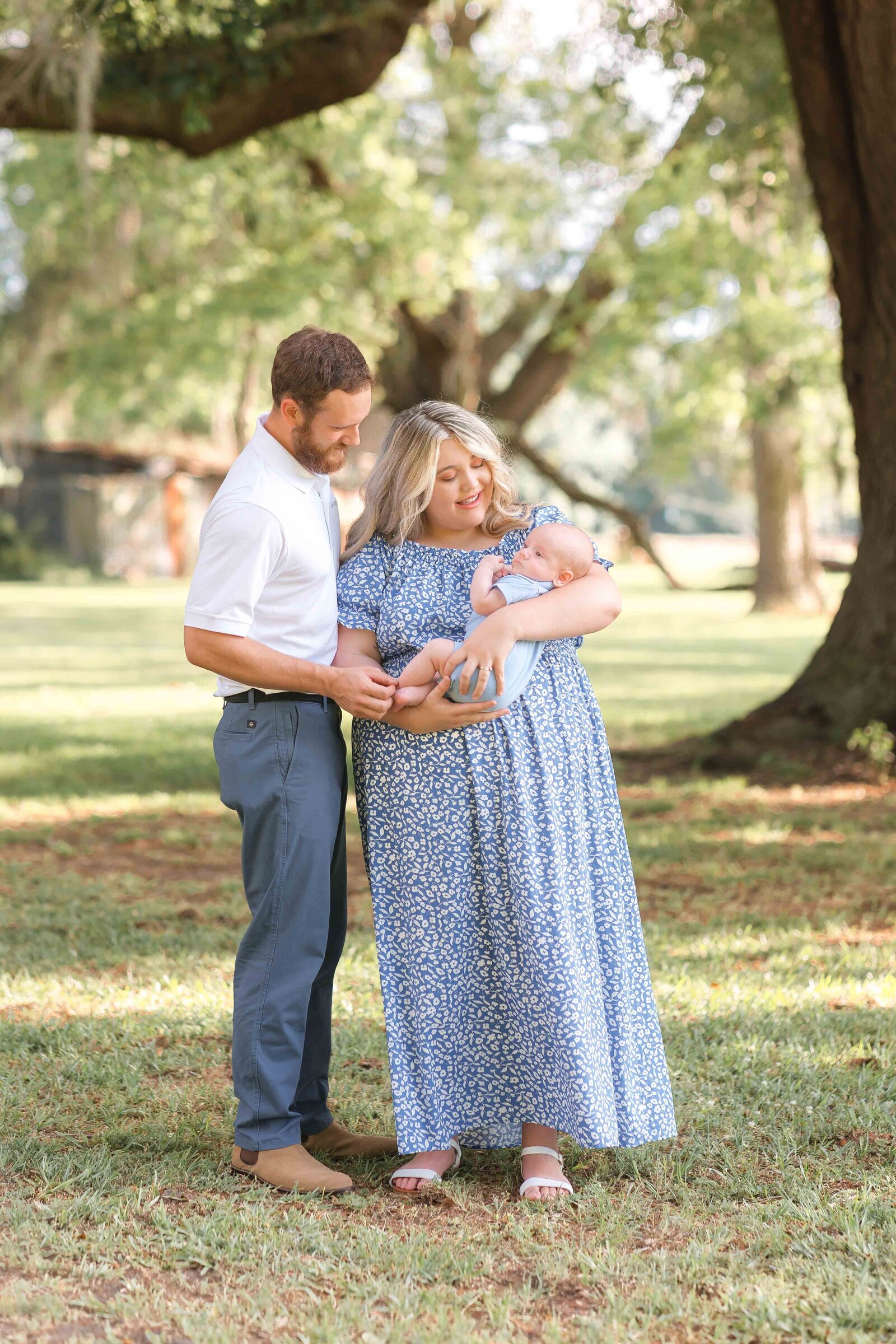 Mom and dad holding 4 month old son and smiling and loving on him at Woodlawn Plantation and Gardens in Guyton, Ga