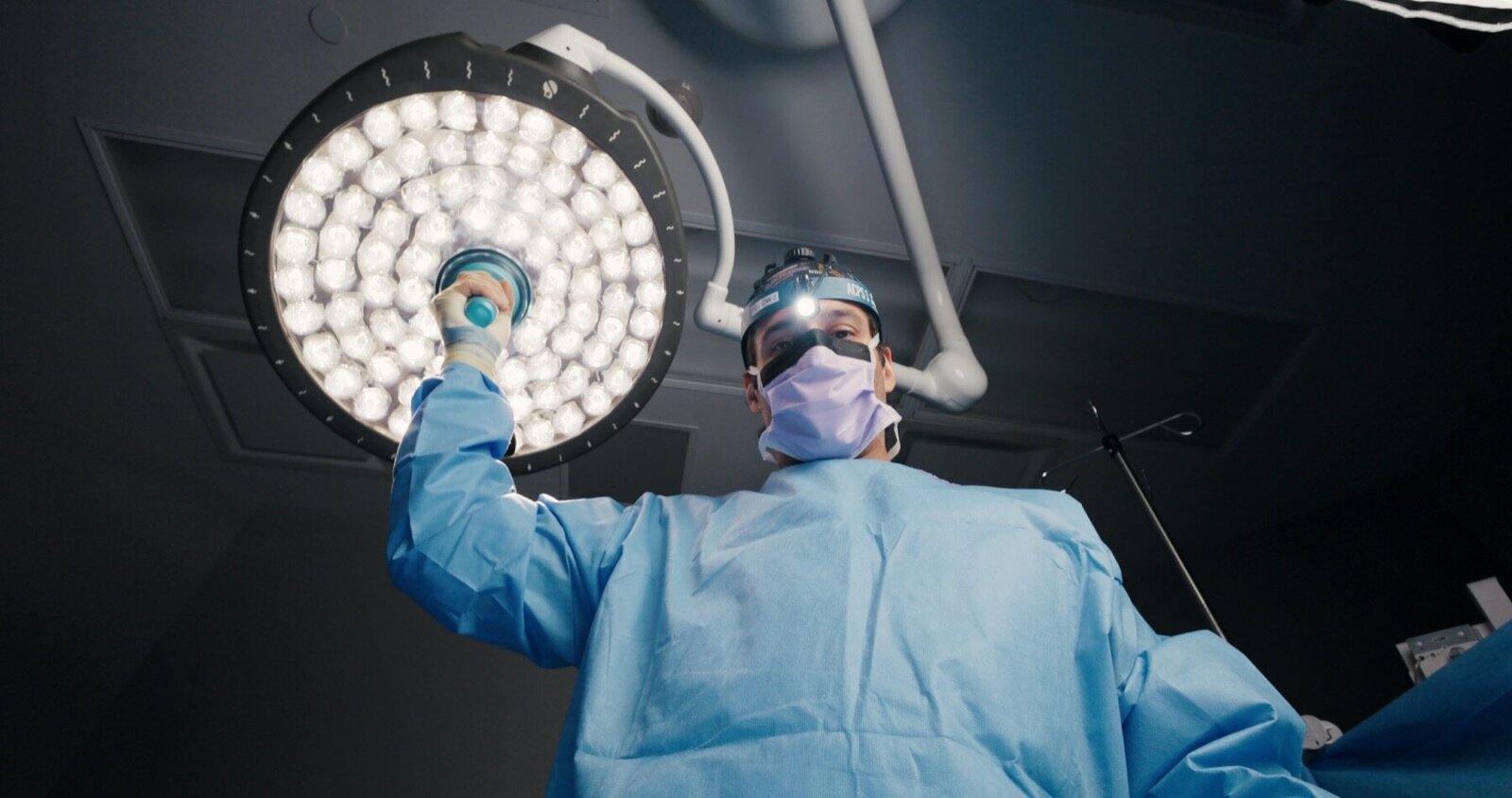 ACPS: surgeon in a gown adjusting the operating room light