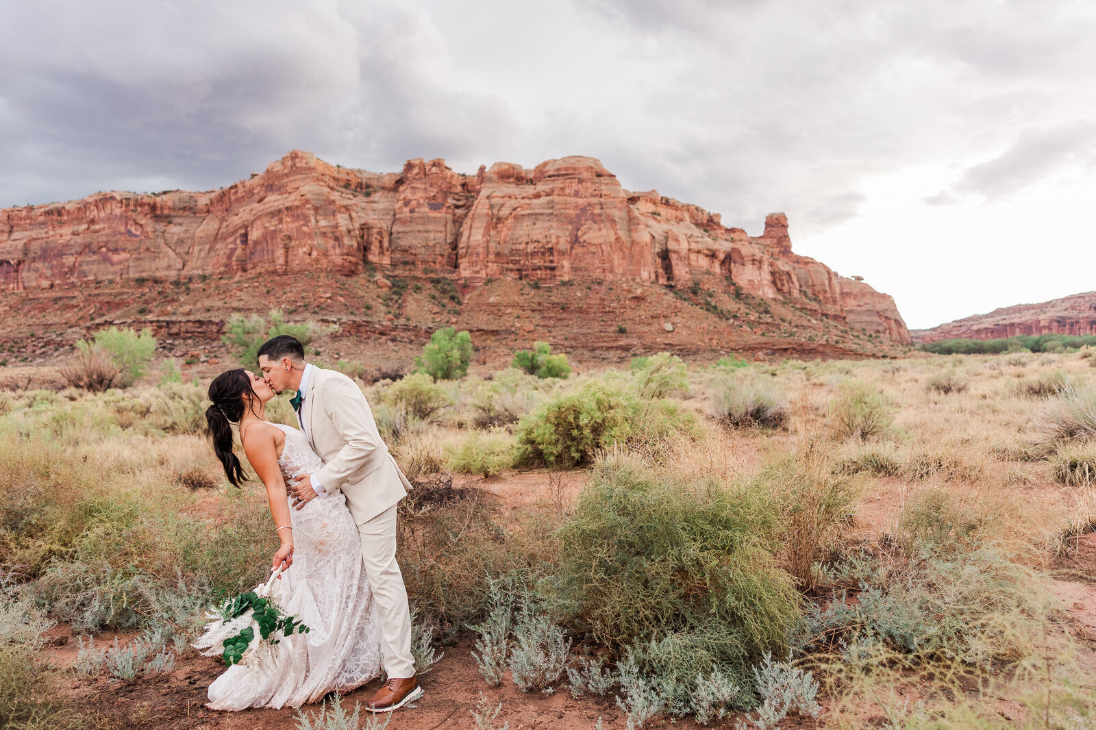 Groom pulls bride into kiss in the desert of Utah