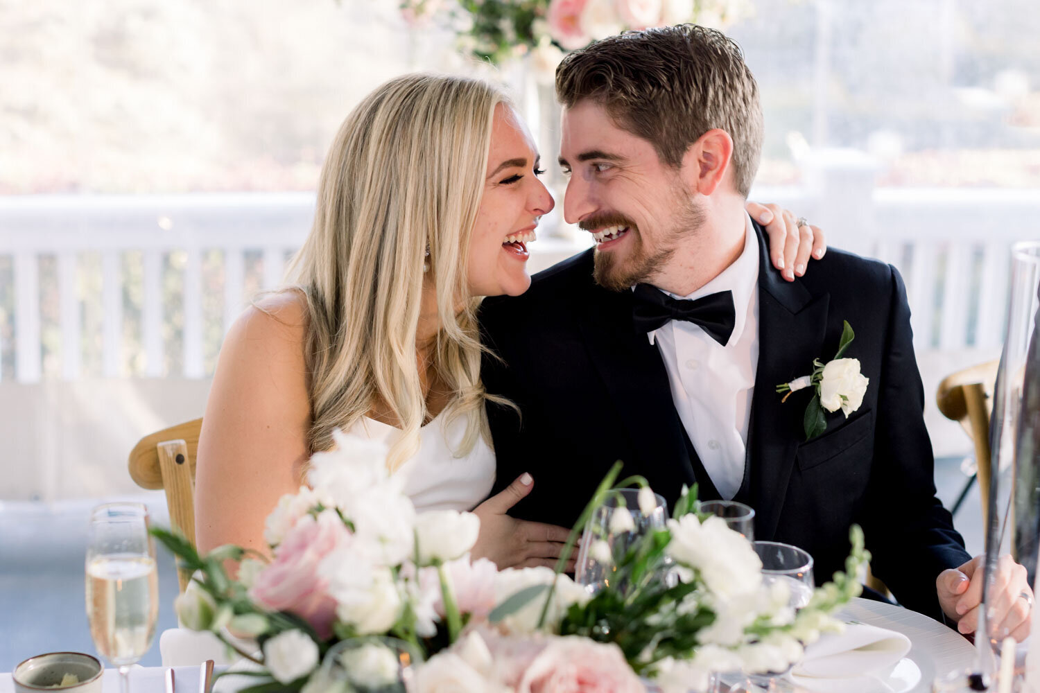 Bride and groom sharing a joyful moment at their reception table