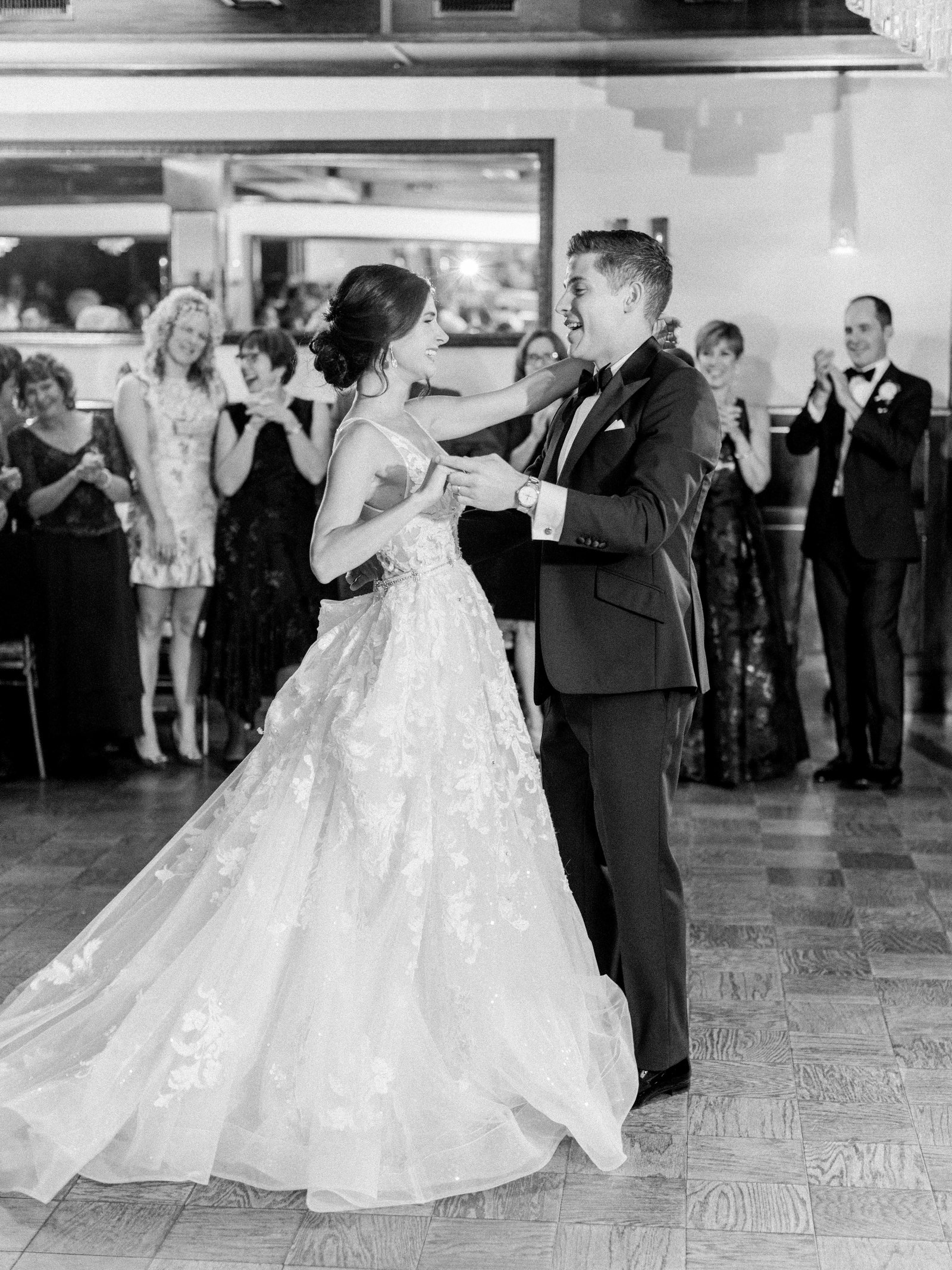 bride and groom spin around the dance floor while all their guest smile and cheer for them in the background