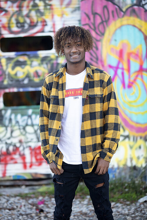 Senior boy  smiles in front of  graffiti wall at photography session