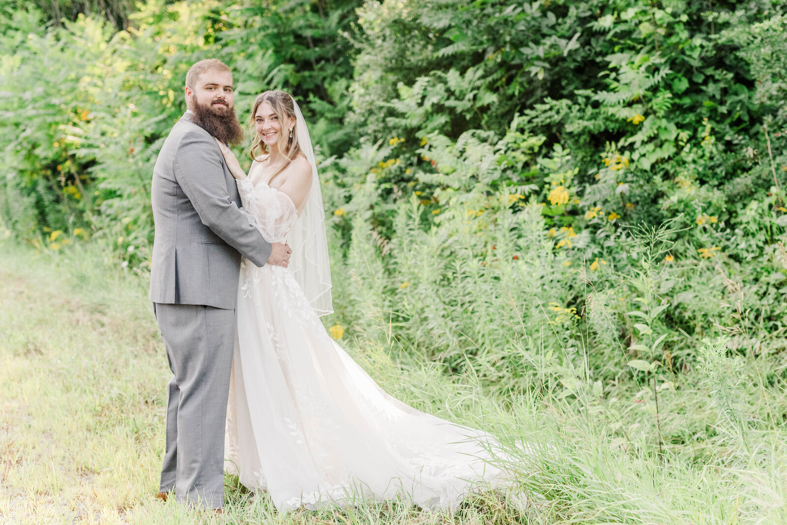 bride and groom posing in tall greenery during wedding photo session in albany ny