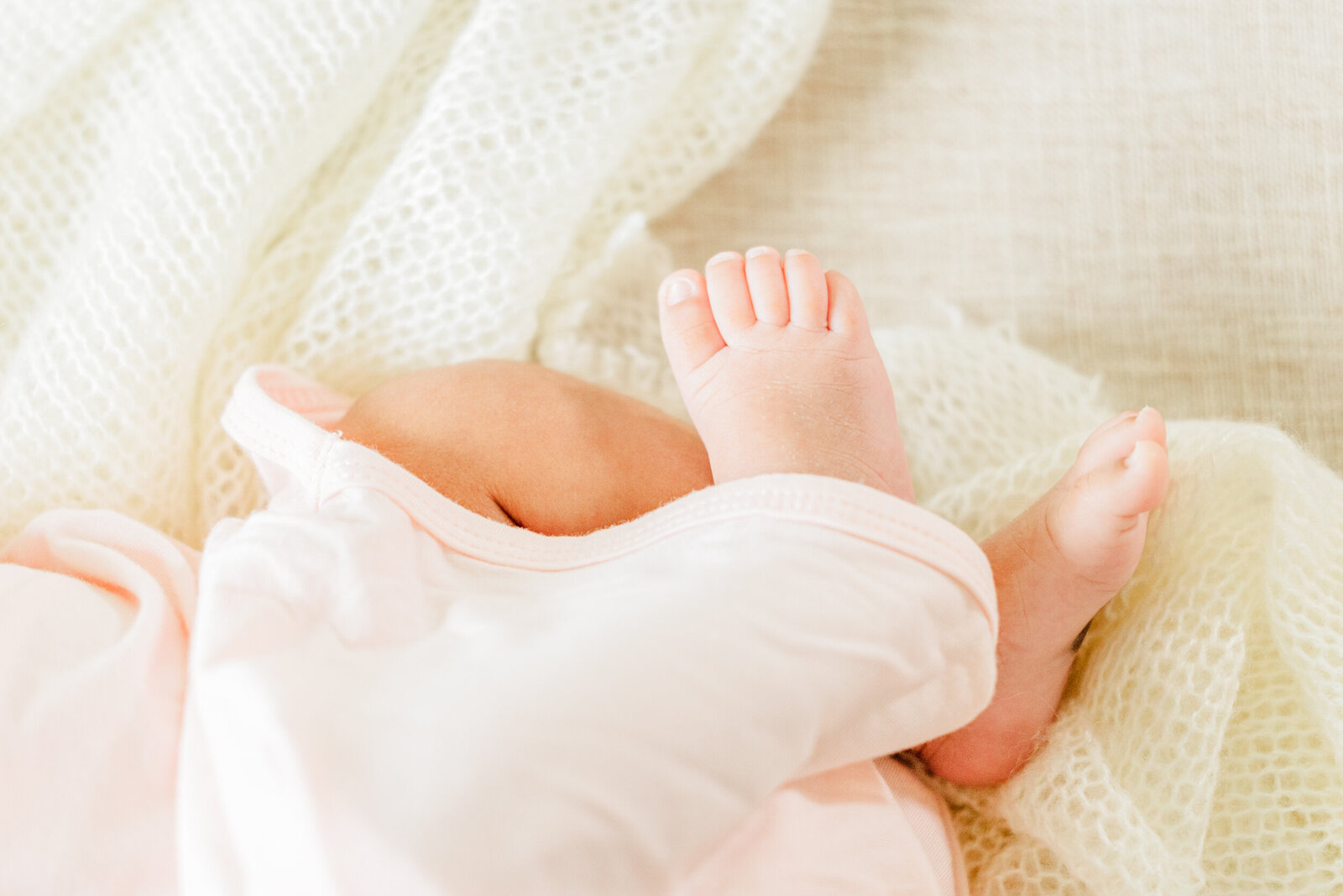 Baby's feet poking out of a pink gown