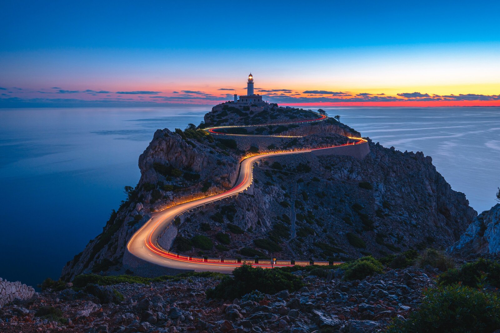 Illuminated road winding up mountain to Cap de Formentor lighthouse in Mallorca, Spain at dusk