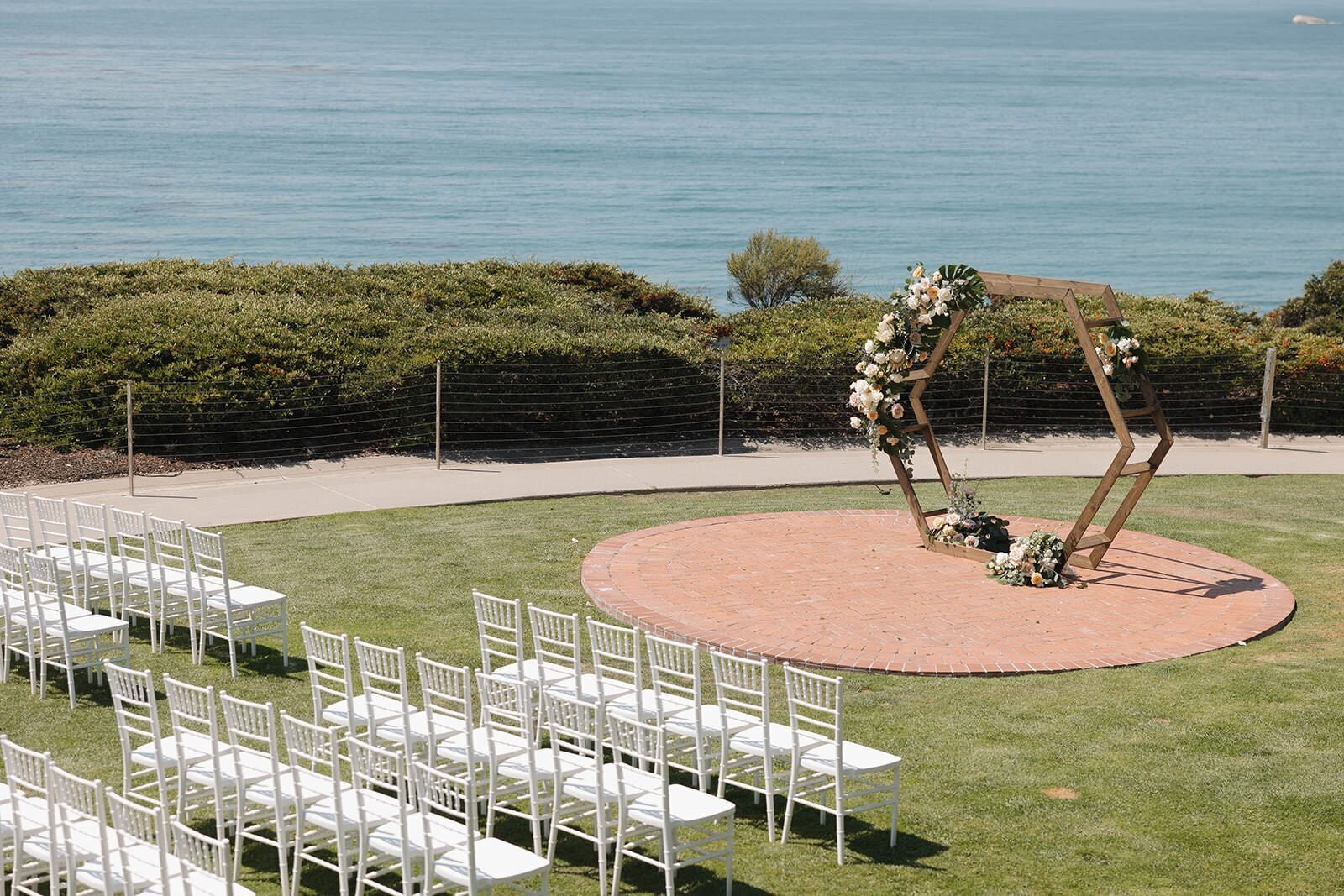Ocean bluff ceremony site with white chairs and a hexagon arbor at The Cliffs in Pismo Beach