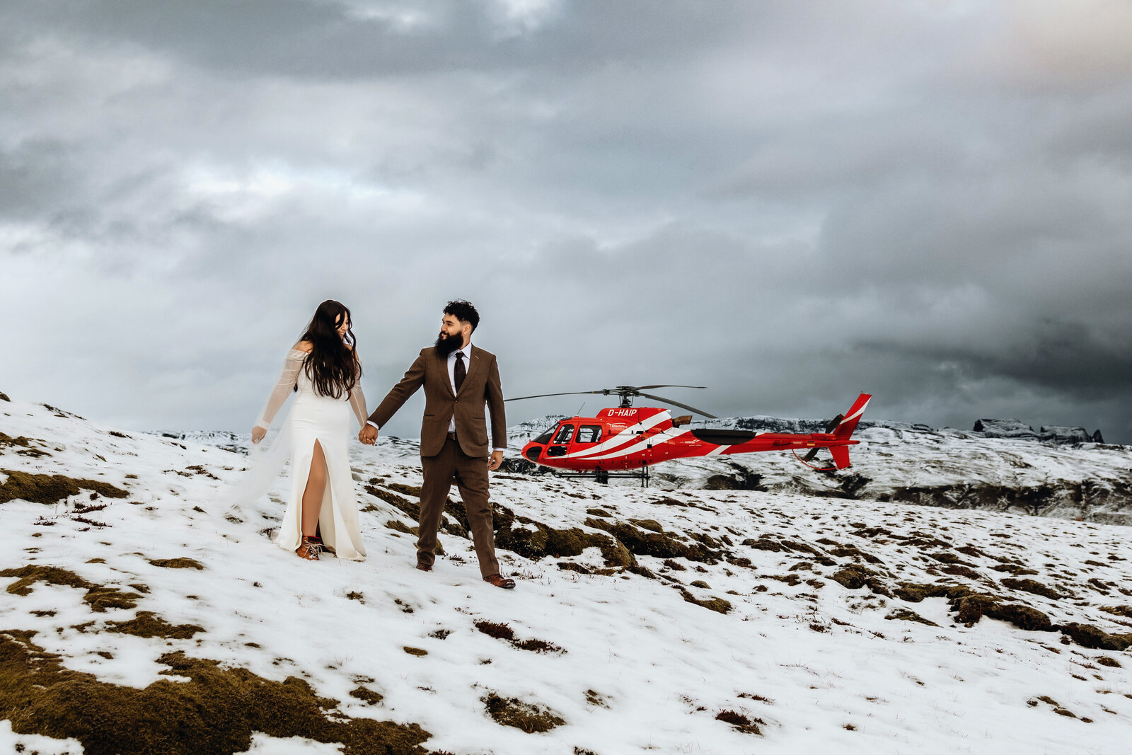 married couple had a helicopter elopement day in Iceland and they are holding hand on top of a snowy mountain