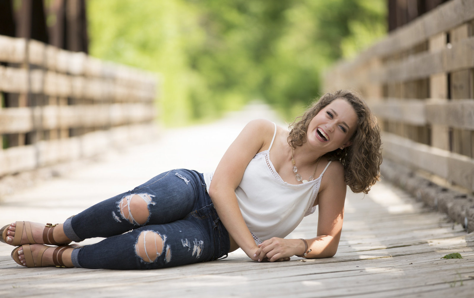 Payten laughs while posing on a bridge during a senior photo shoot