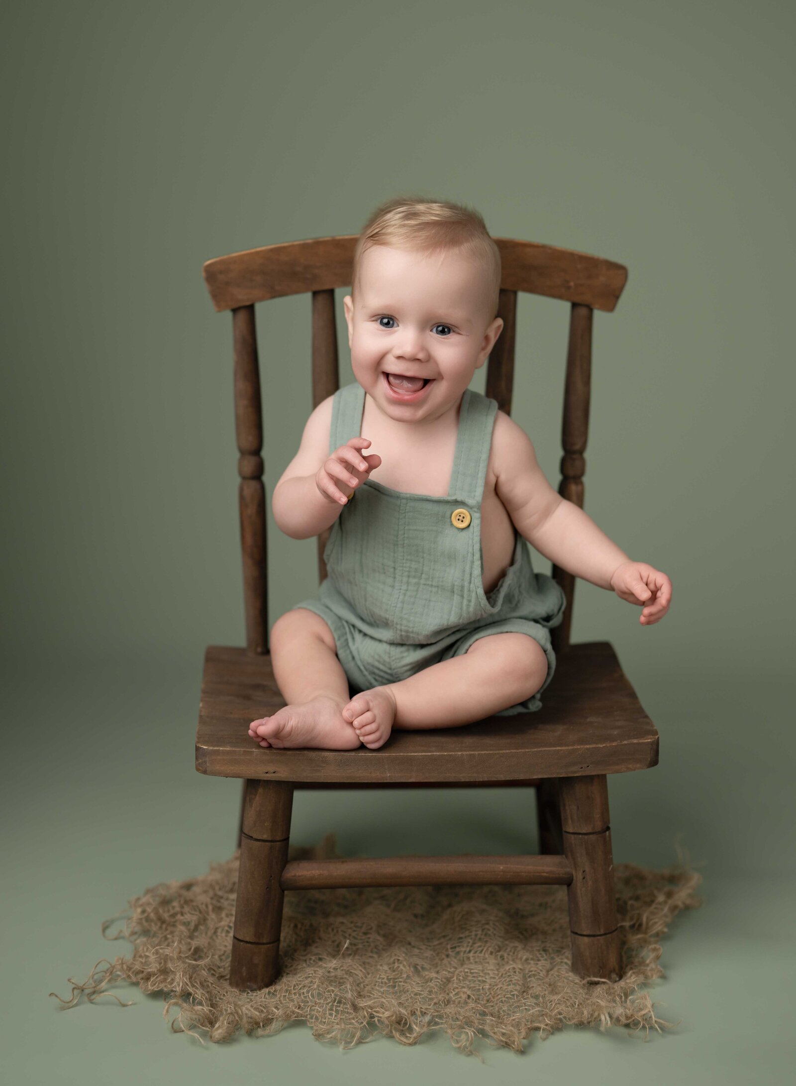 milestone studio photo of baby boy sitting up on brown chair. Baby milestone photo taken by Jenni Nikki Photography in Atlanta, GA. 