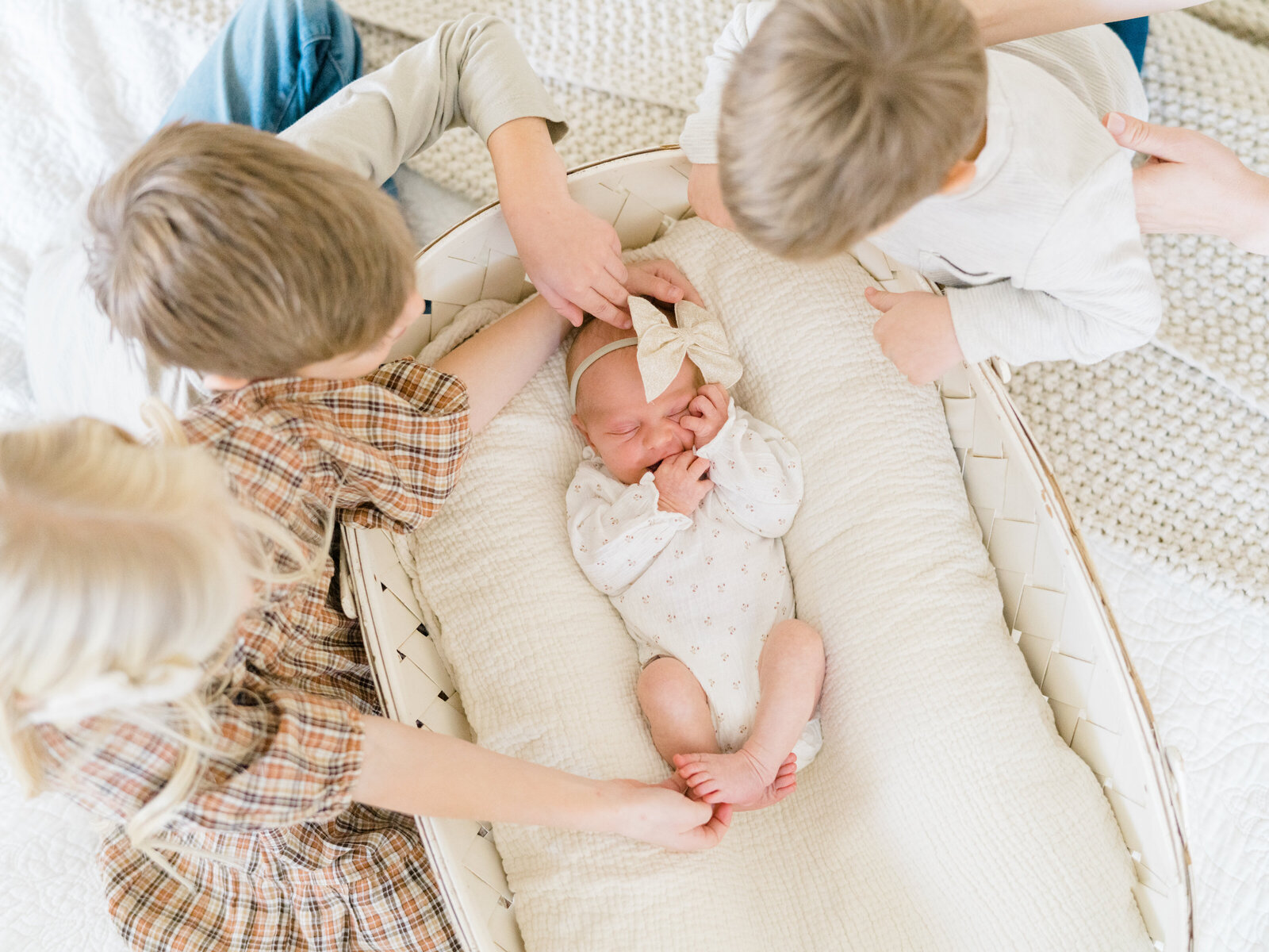 two big brothers and one big sister looking down at their new little baby sister
