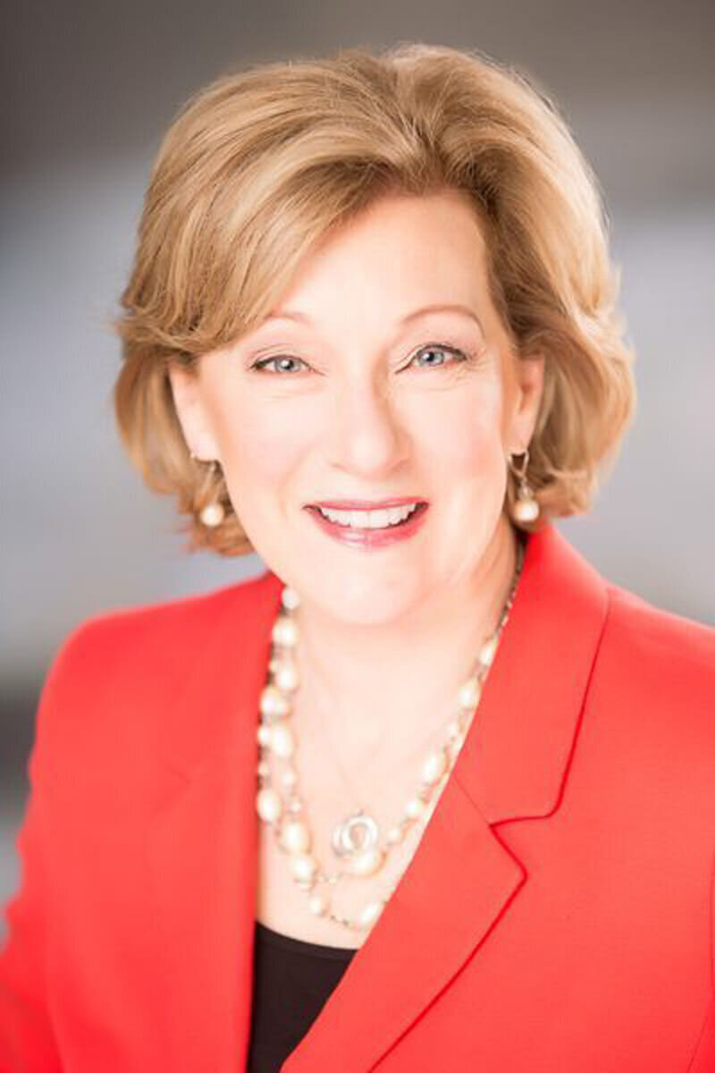 Corporate headshot of woman with pearl earrings and red blazer