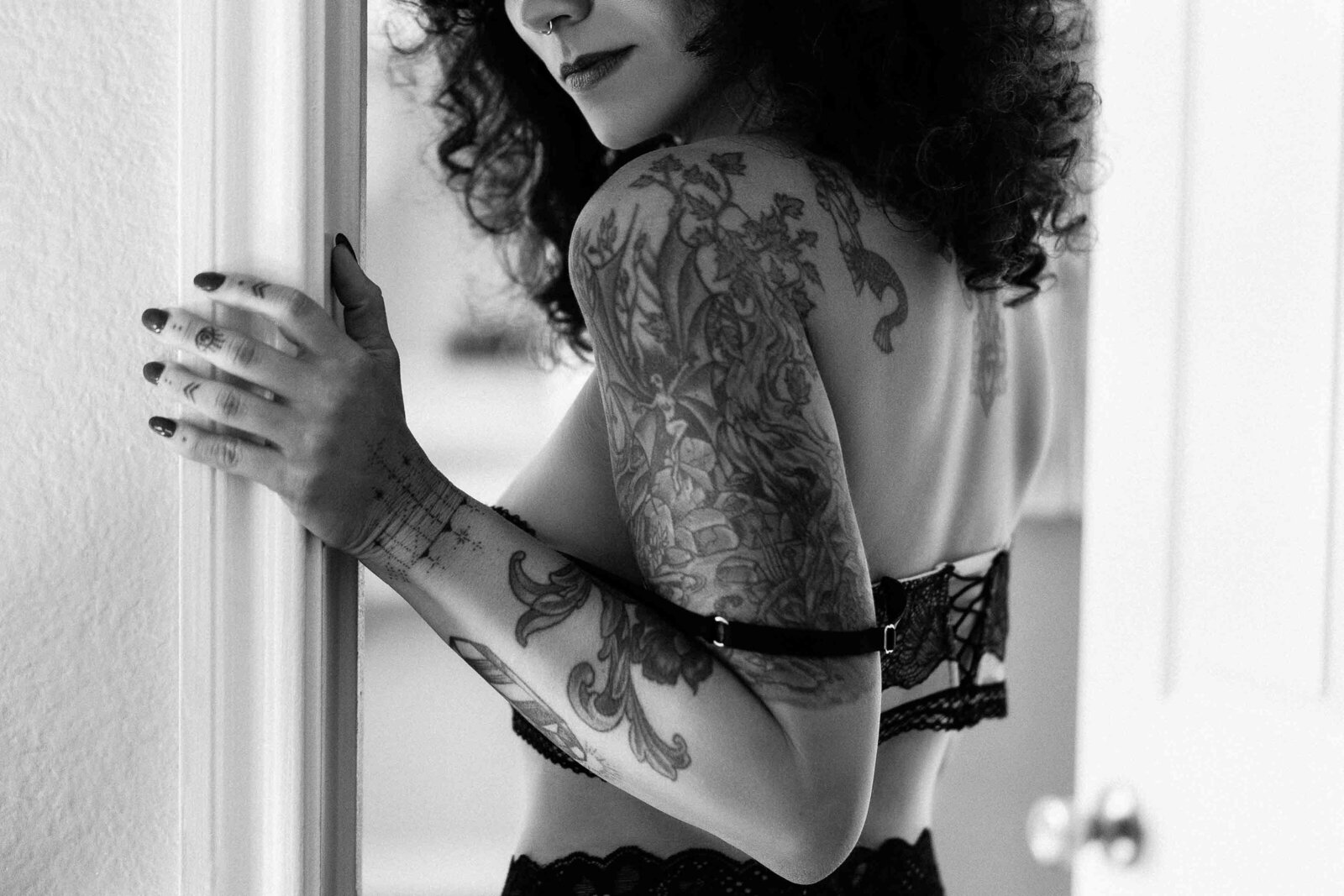 tattooed woman undressing at bedroom door