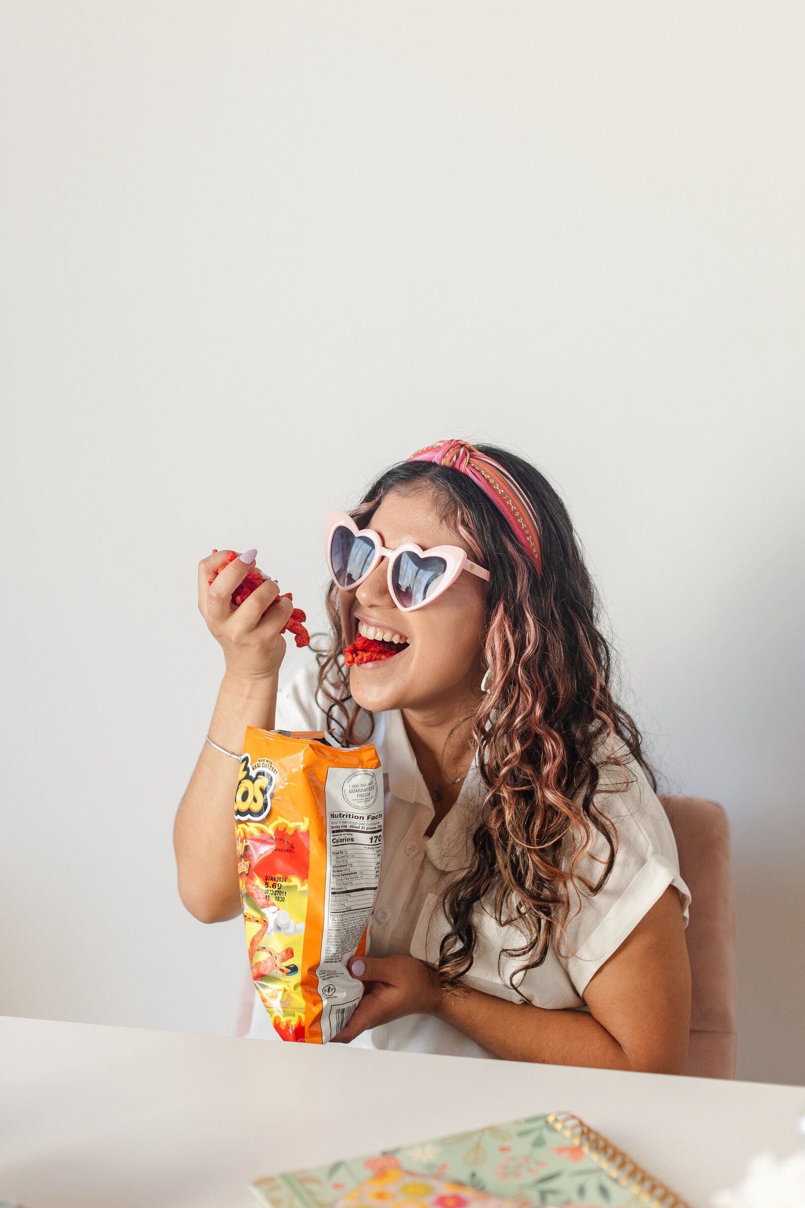 a wedding photographer smiles and eats flaming hot cheetos