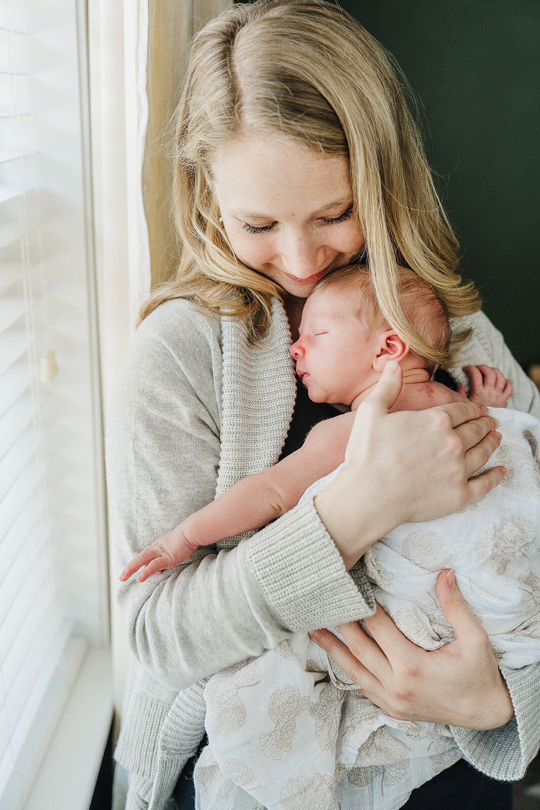 mom snuggles newborn baby to chest during boston newborn photos