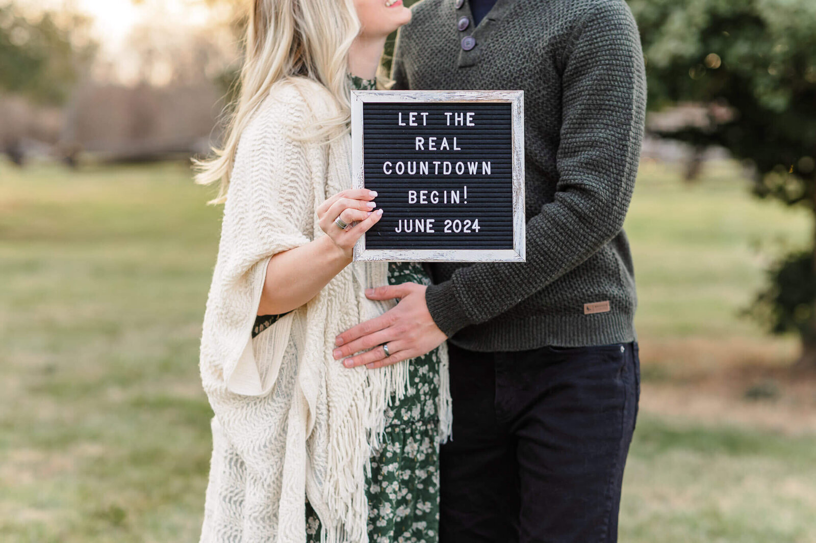 A sign announcing a pregnancy being held by a couple.