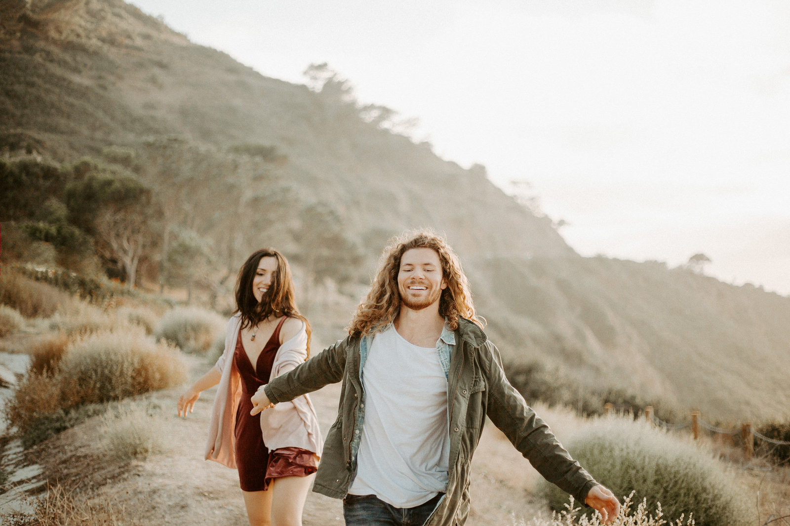 Couple holding hands walking together by a hill during their engagement session