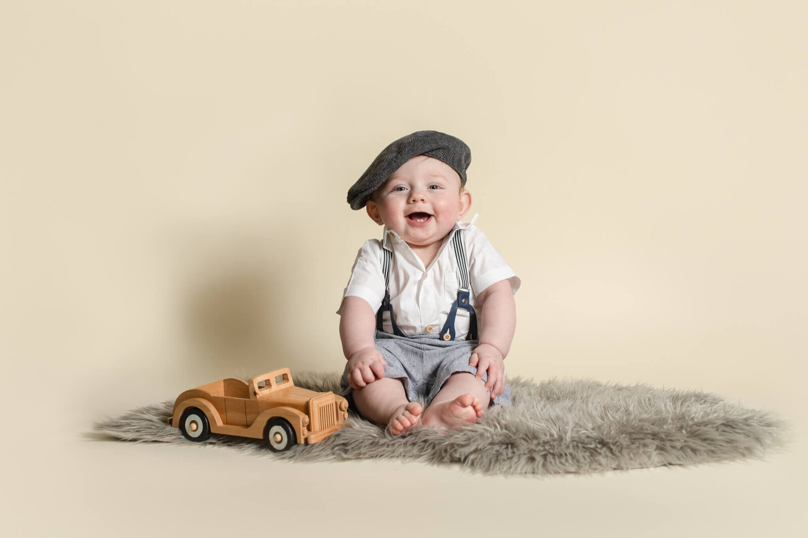Baby boy in studio smiling sitting on gray flokati rug