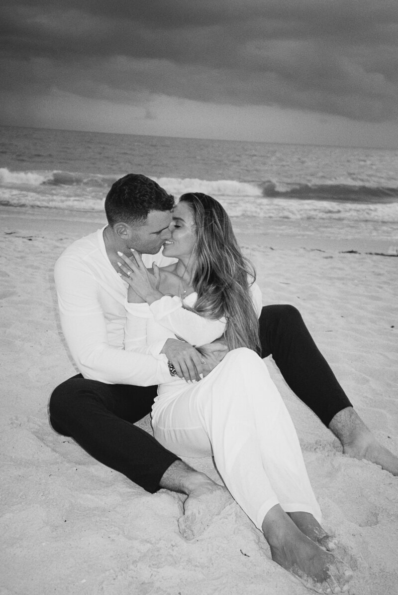 couple kissing on beach for engagement photos in Naples