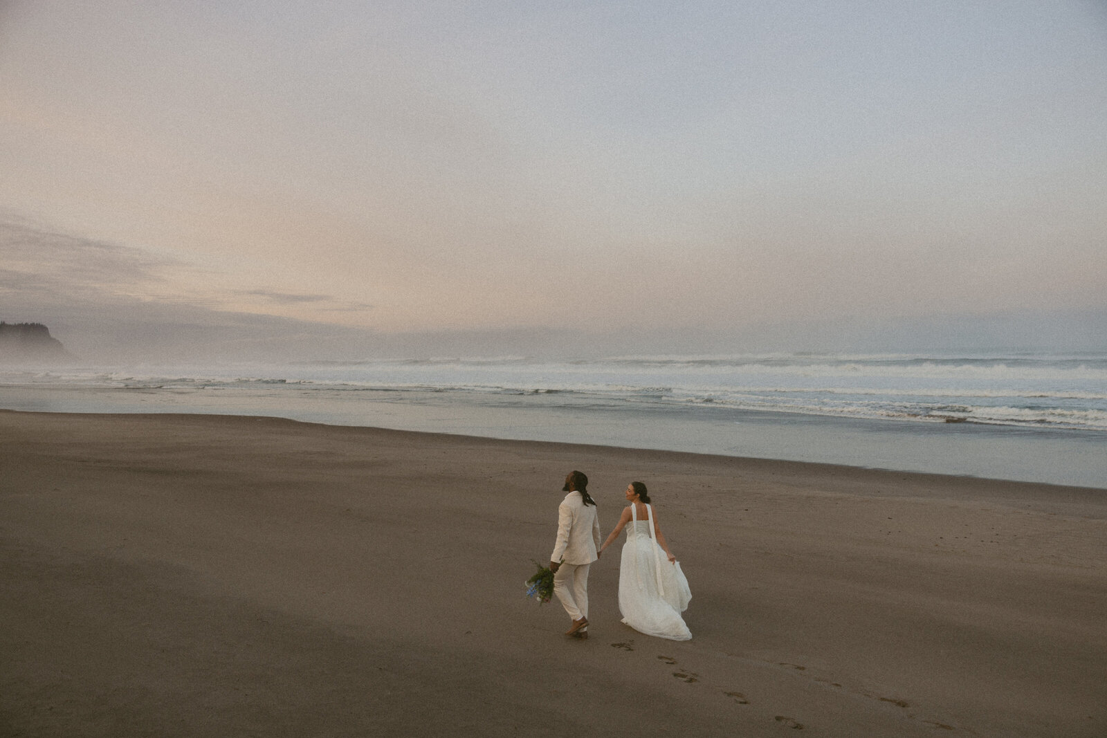 Couple walking on a beach in Tofino, captured by Vancouver Island elopement photographer Rae Terrillon