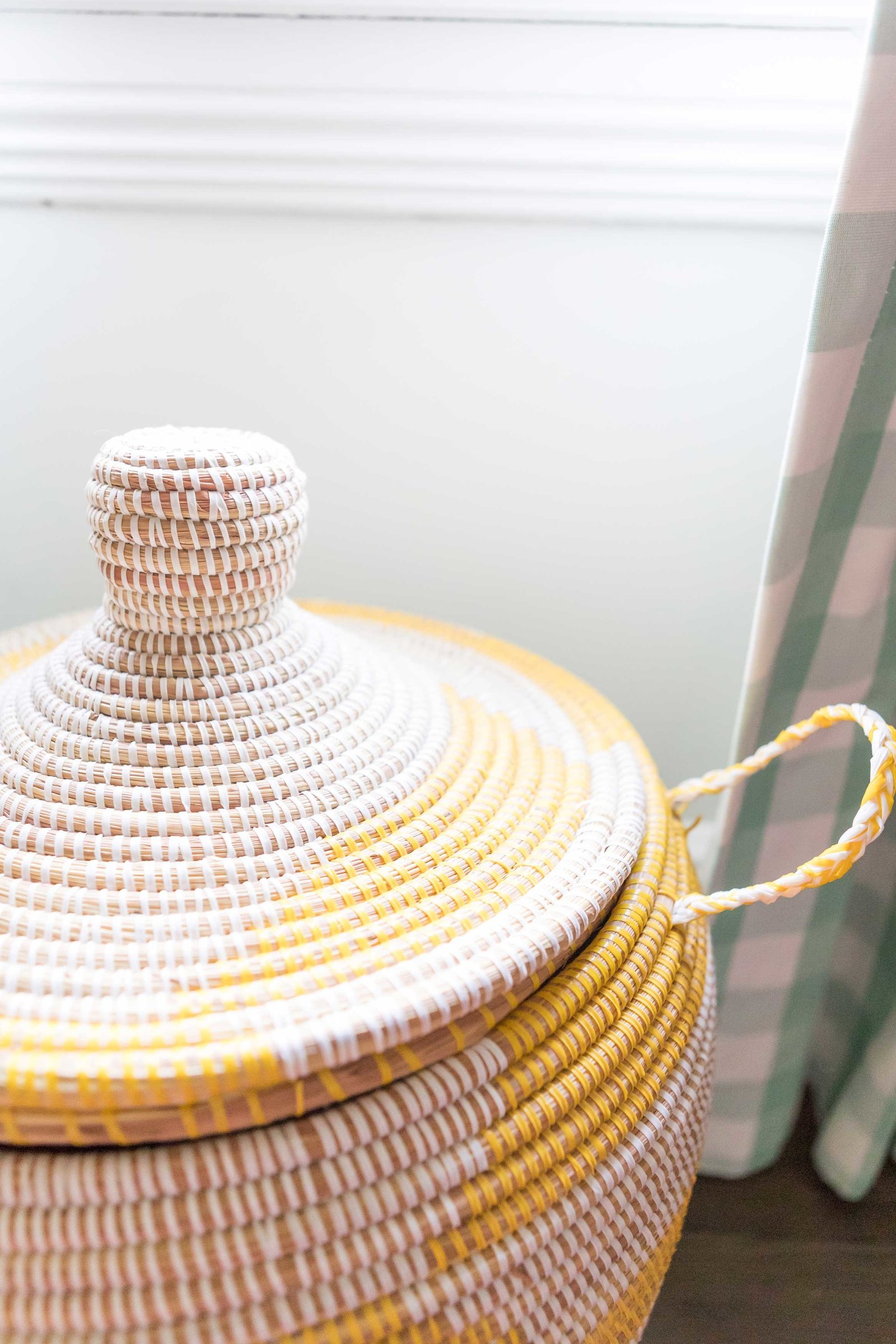 A natural and yellow woven basket with lid.
