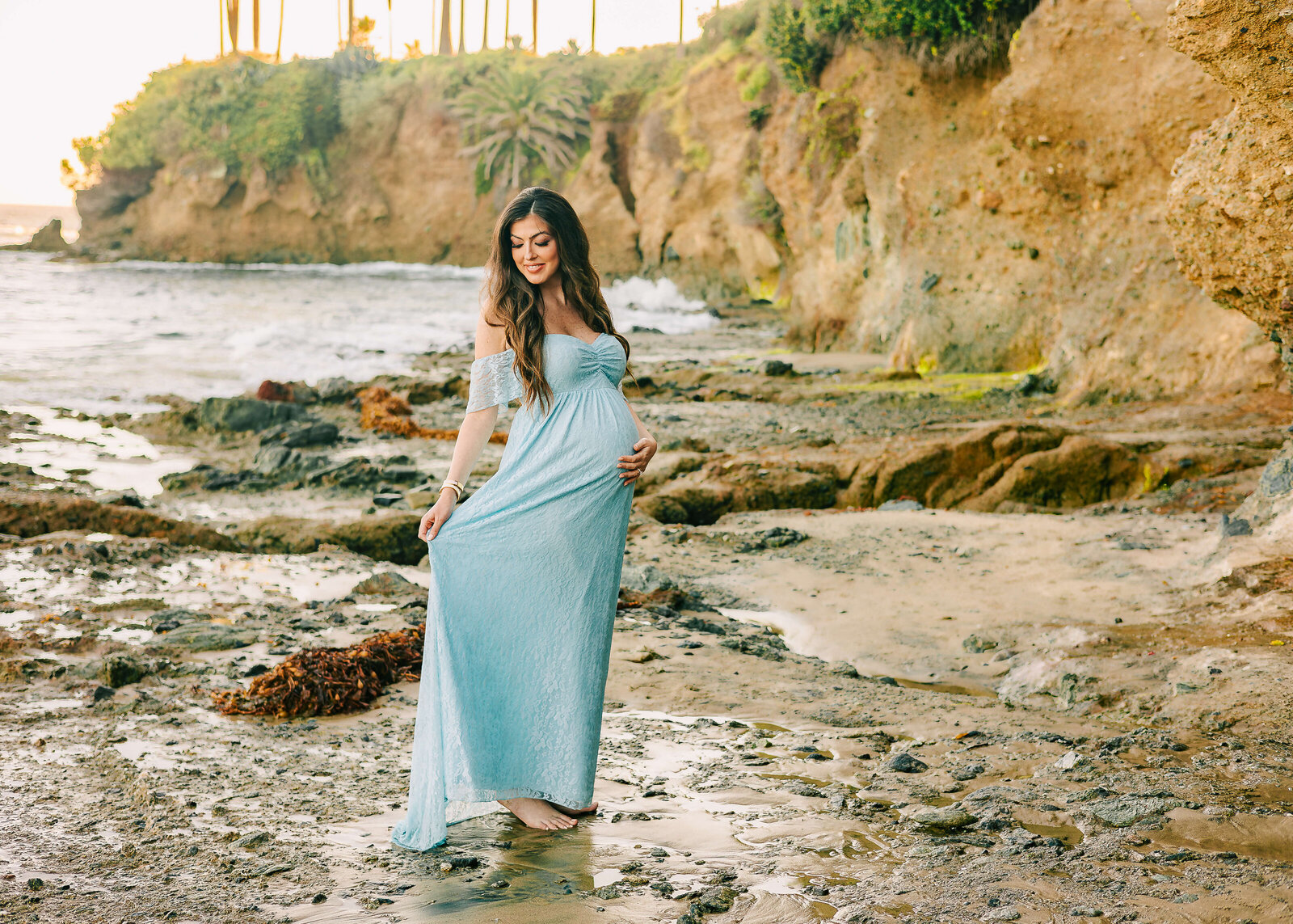 Expectant mom twirling her blue lace dress during maternity session in Laguna Beach by Ashley Nicole.