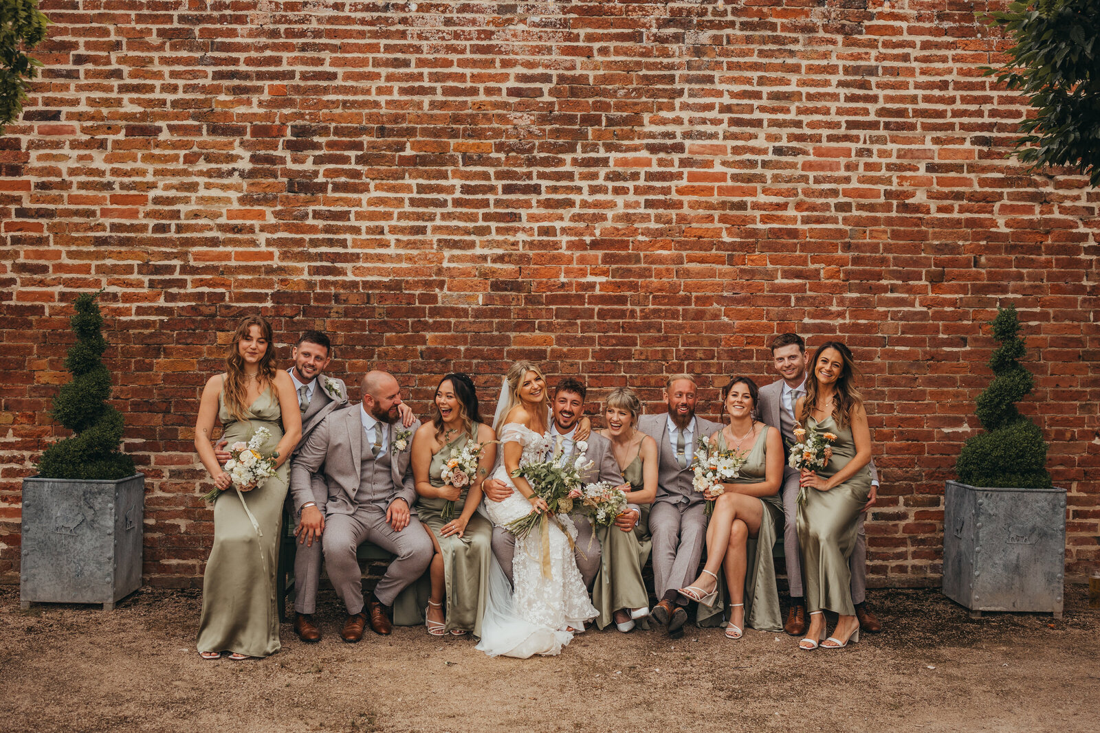 wedding party pose in front of red brick wall