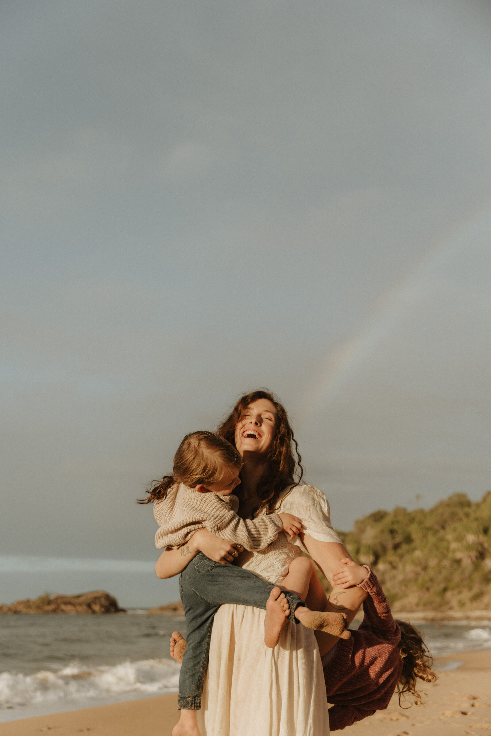 Mother holding her kids, laughing on the beach