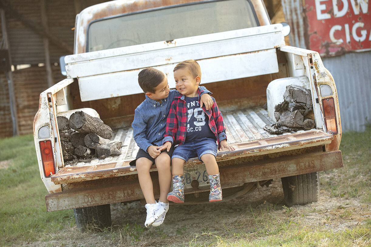 Siblings playing in the back of vintage pick-up truck during Dallas family photoshoot.