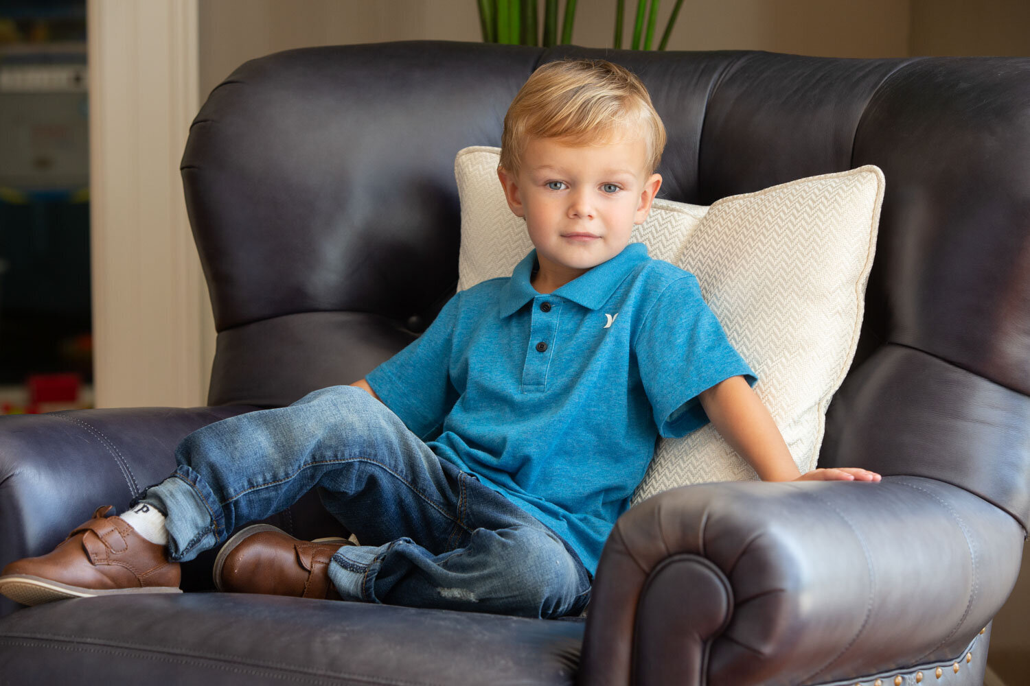 Handsome baby boy in blue polo shirt sitting on a sofa